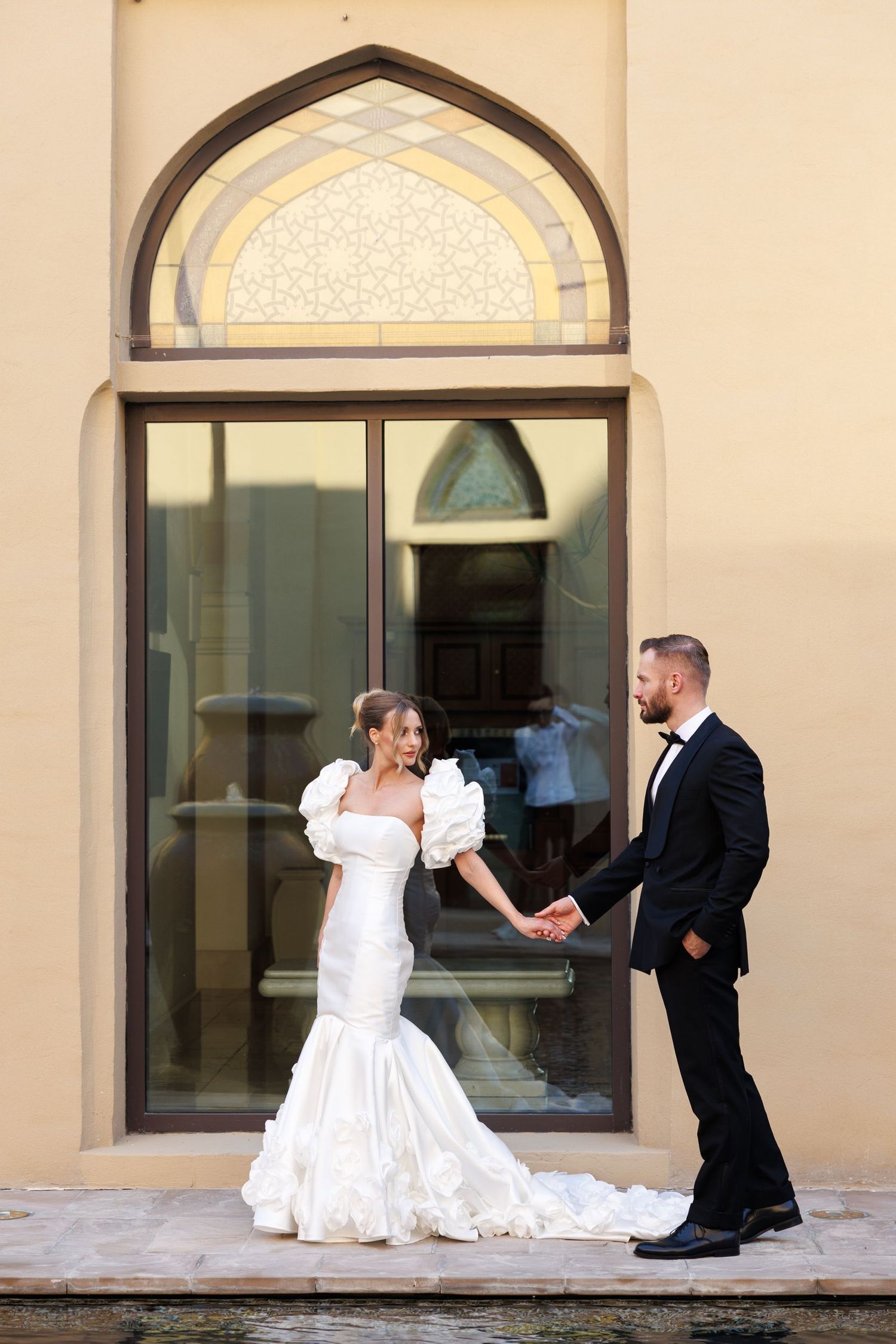 A playful wedding photoshoot sequence outside a building with arched windows.