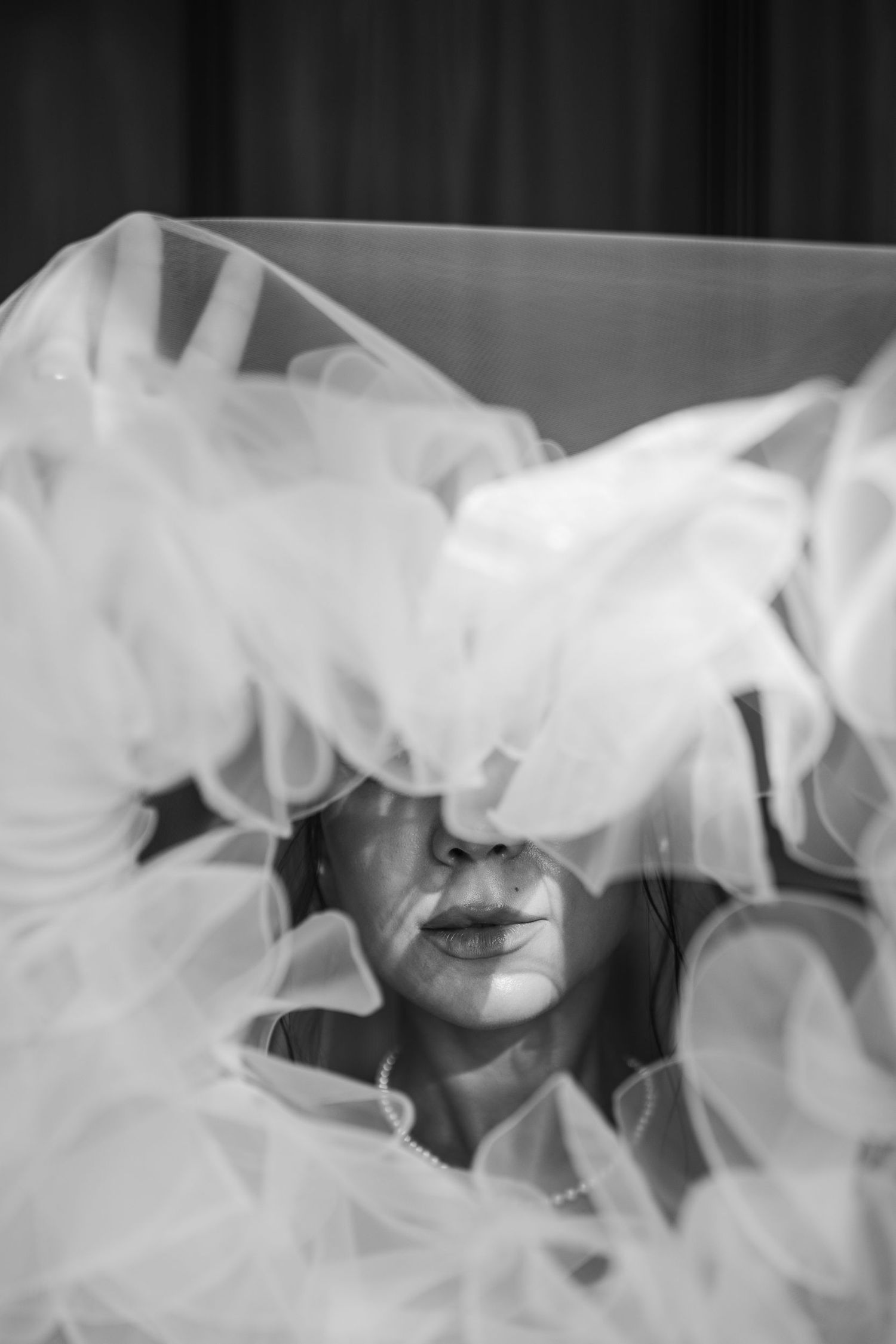 Ethereal black and white portrait through flowing white veil creating dreamy effect.