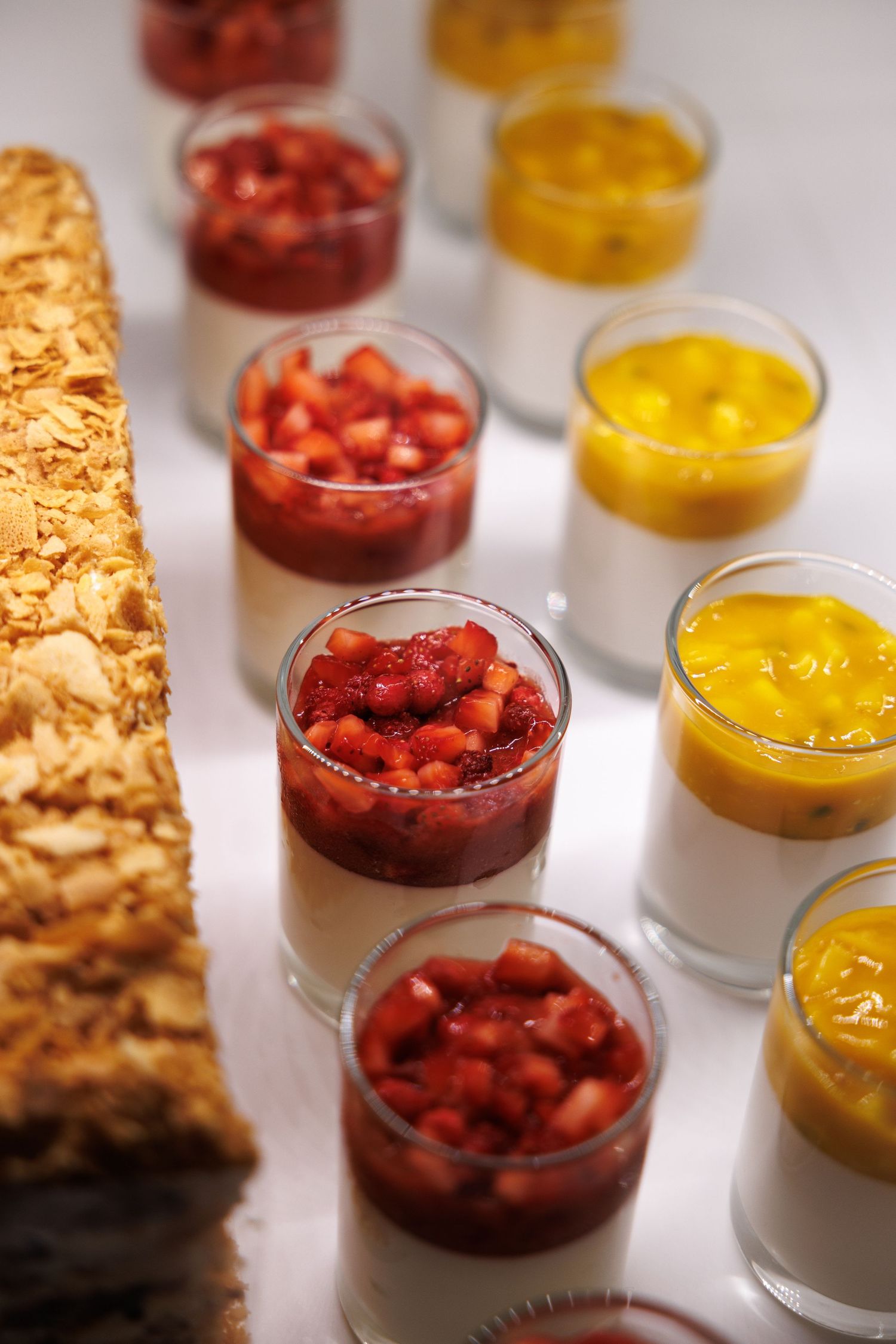 Elegant dessert presentation with alternating red berry and yellow custard parfaits.
