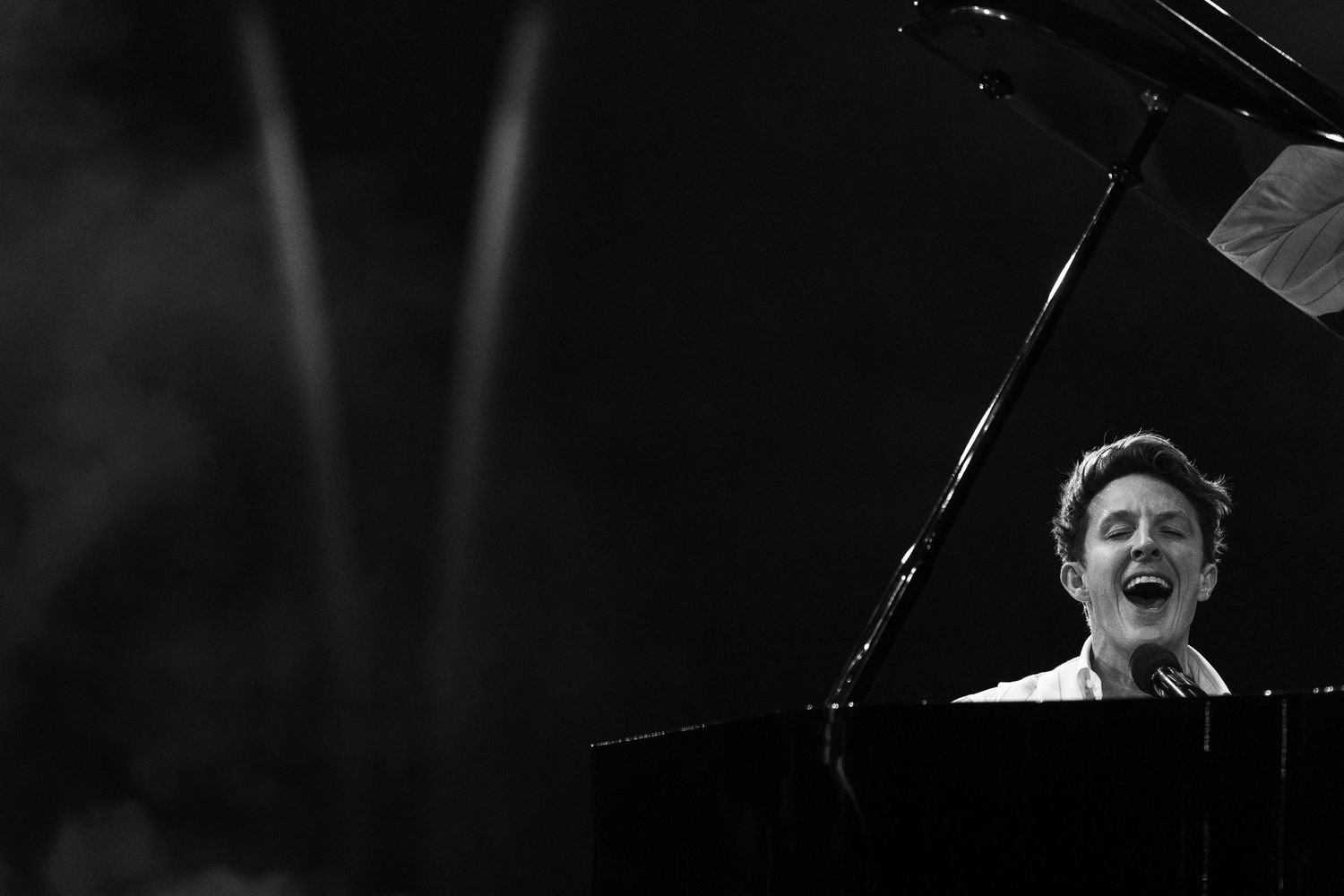 Dramatic performance at a grand piano on a dimly lit stage.
