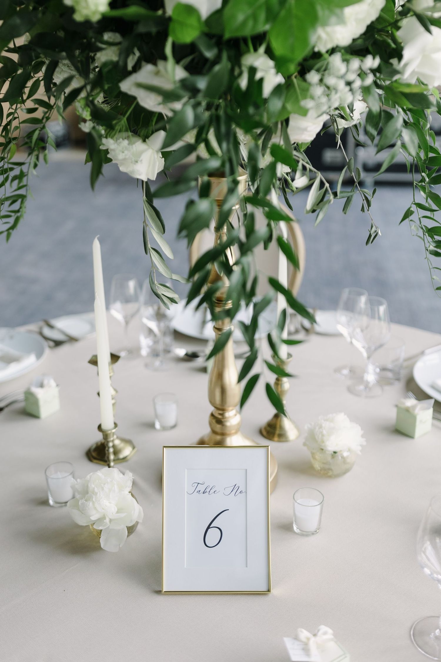Elegant table setting with white floral centerpiece, candles and table number 6 card.