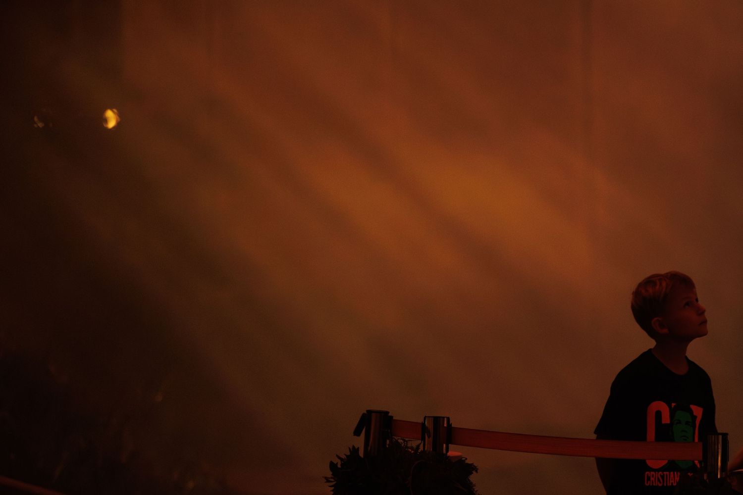 Silhouette of a performer against dramatic orange stage lighting and fog effects.