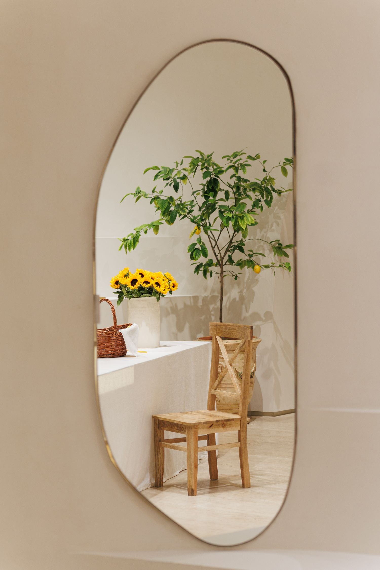 Mirror reflection showing wooden chair and sunflowers through arched doorway.