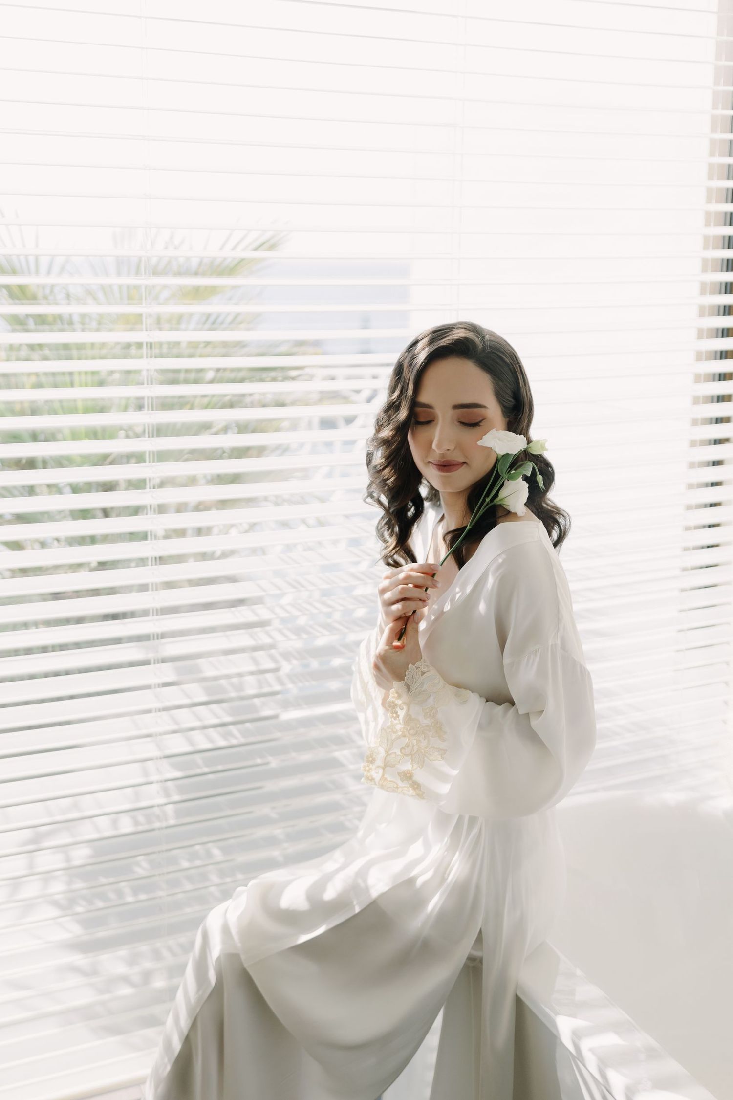 Ethereal bridal portrait by a window with soft natural lighting and white fabric.
