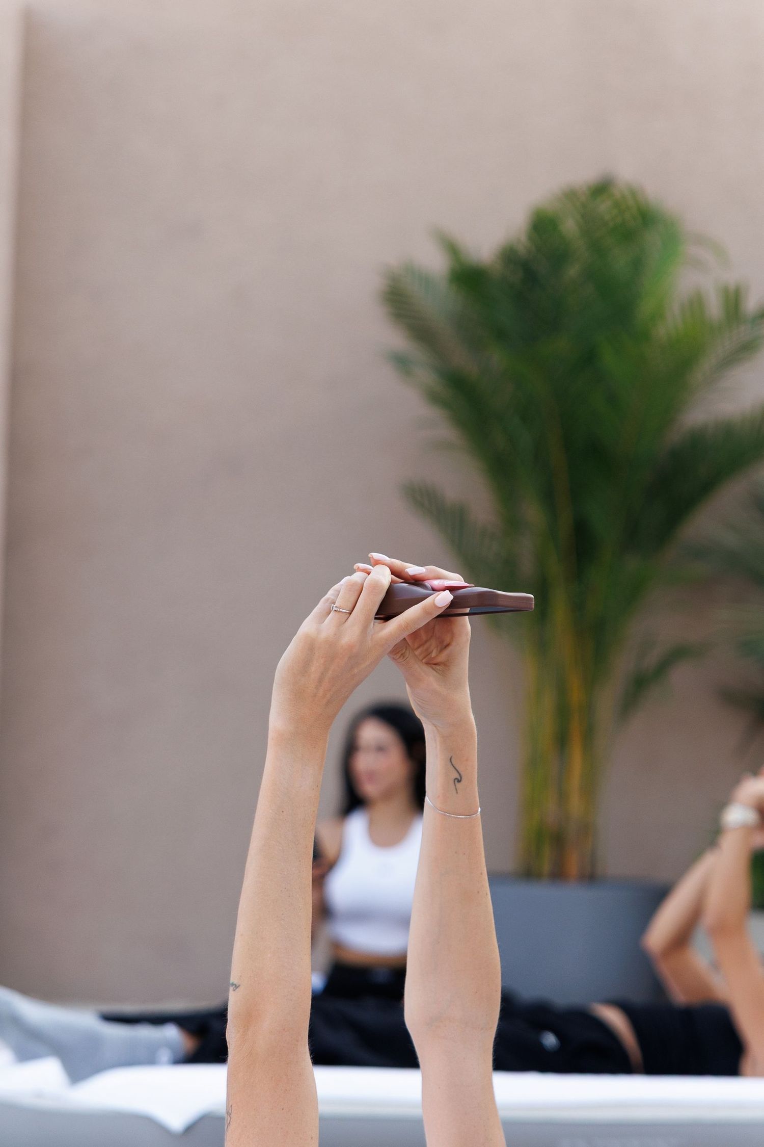 Hands raised in a meditative pose during a wellness session by the pool.