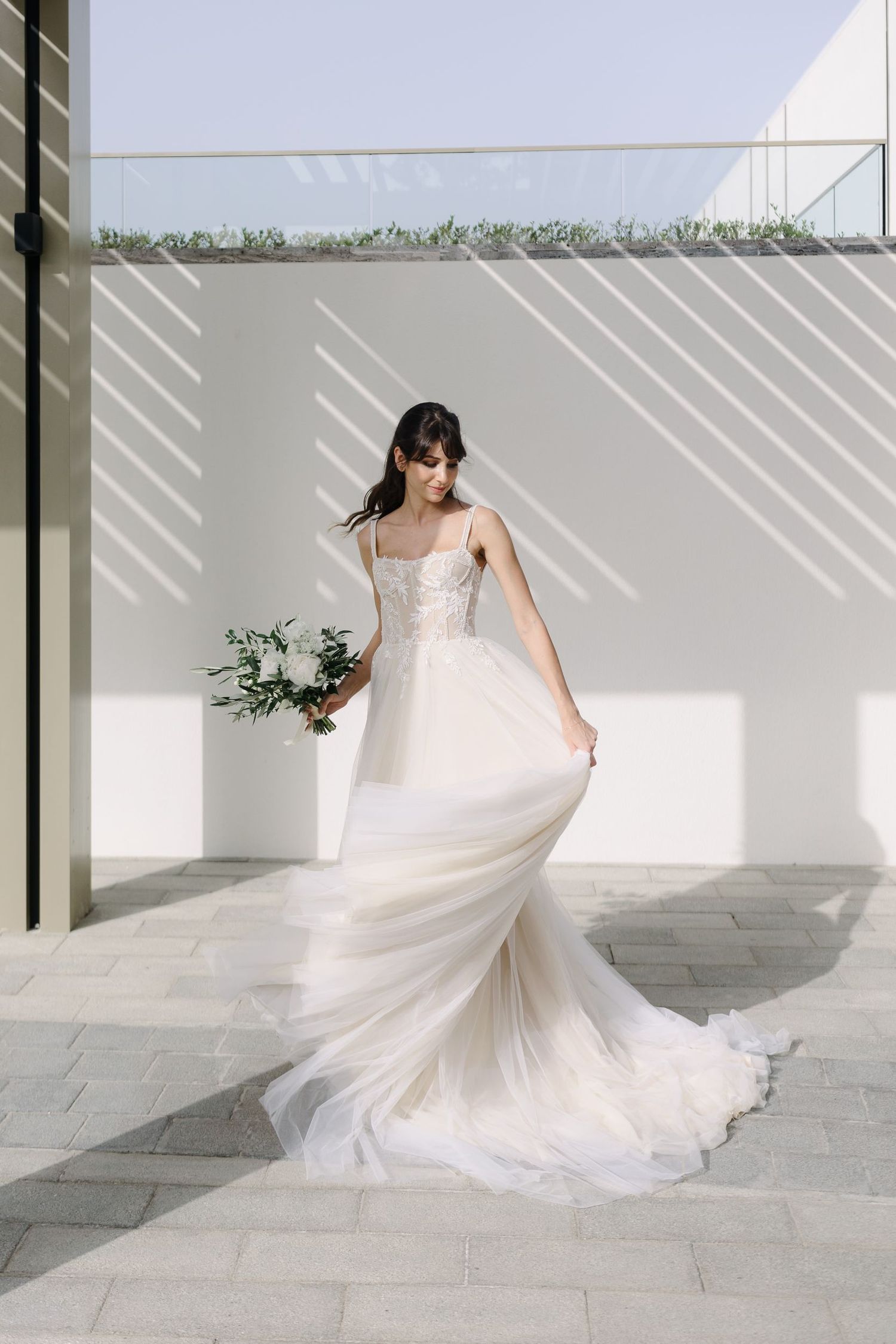 Flowing white wedding gown with lace details twirling in an elegant outdoor setting.