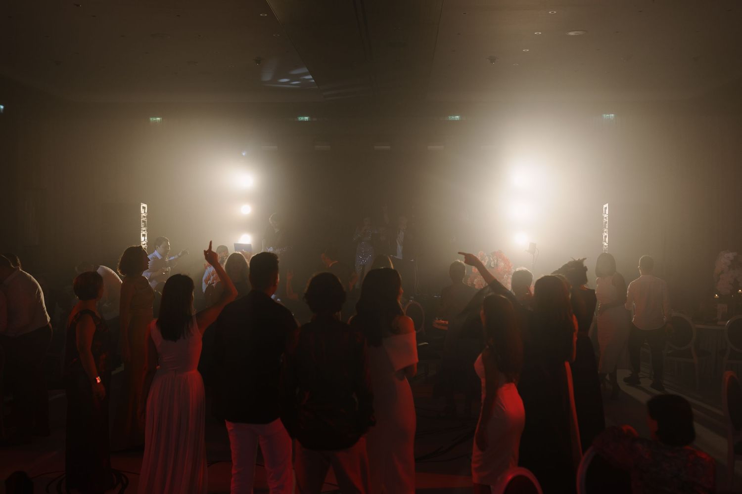 Silhouetted crowd gathered in a dark reception hall with dramatic spotlighting.