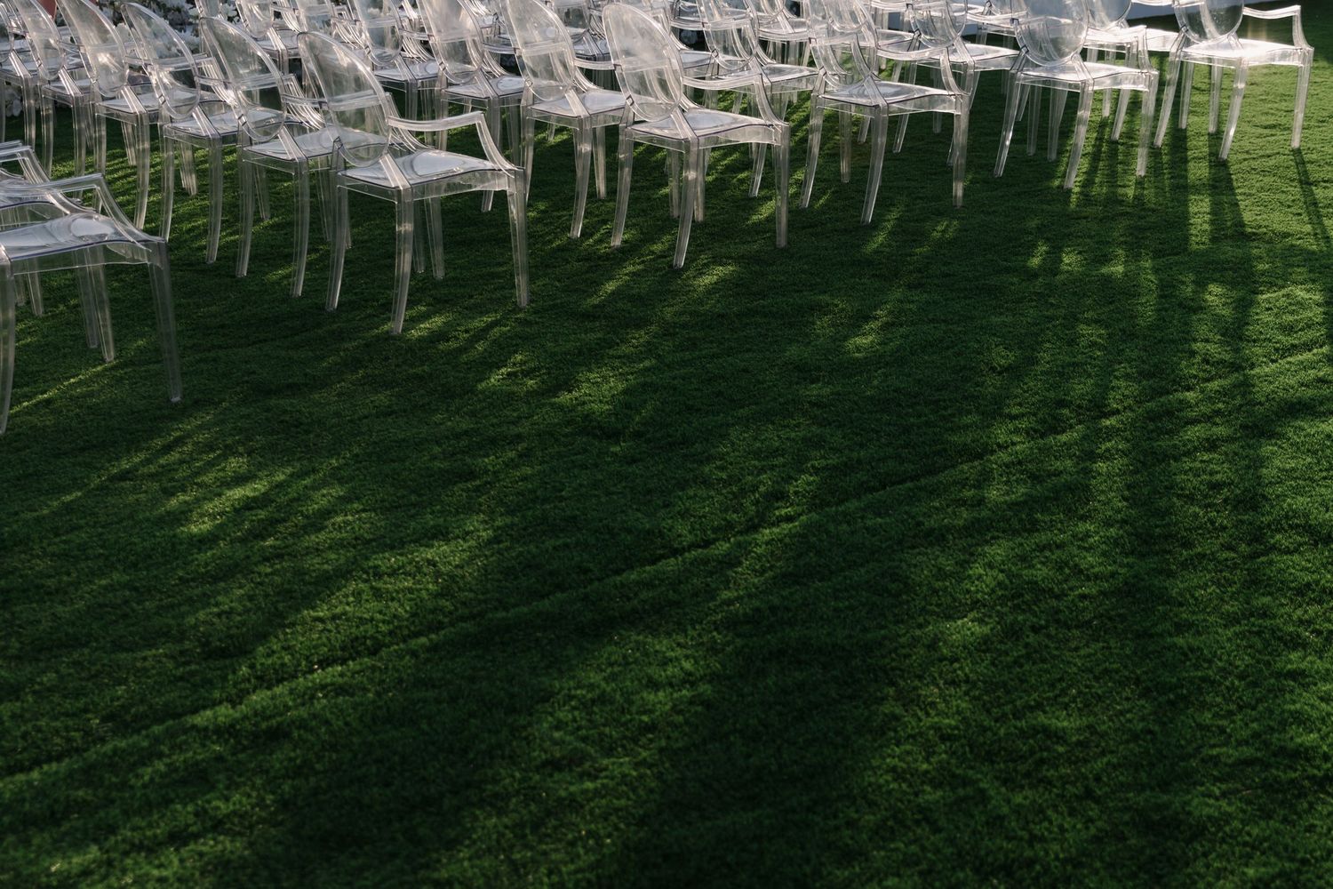Rows of white wedding chairs set up on a manicured lawn for an outdoor ceremony.