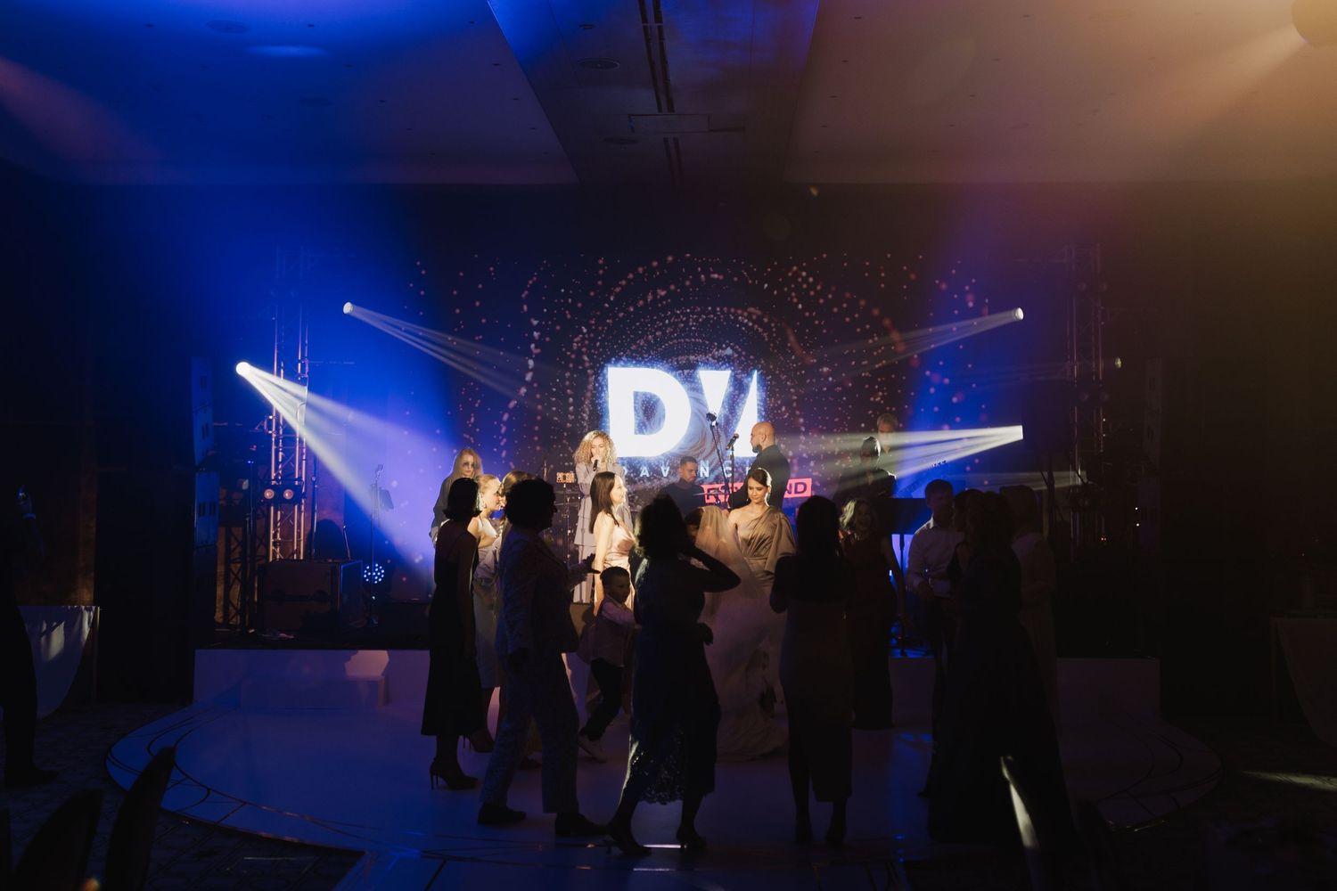 Concert venue with dramatic blue stage lighting and silhouetted audience members.