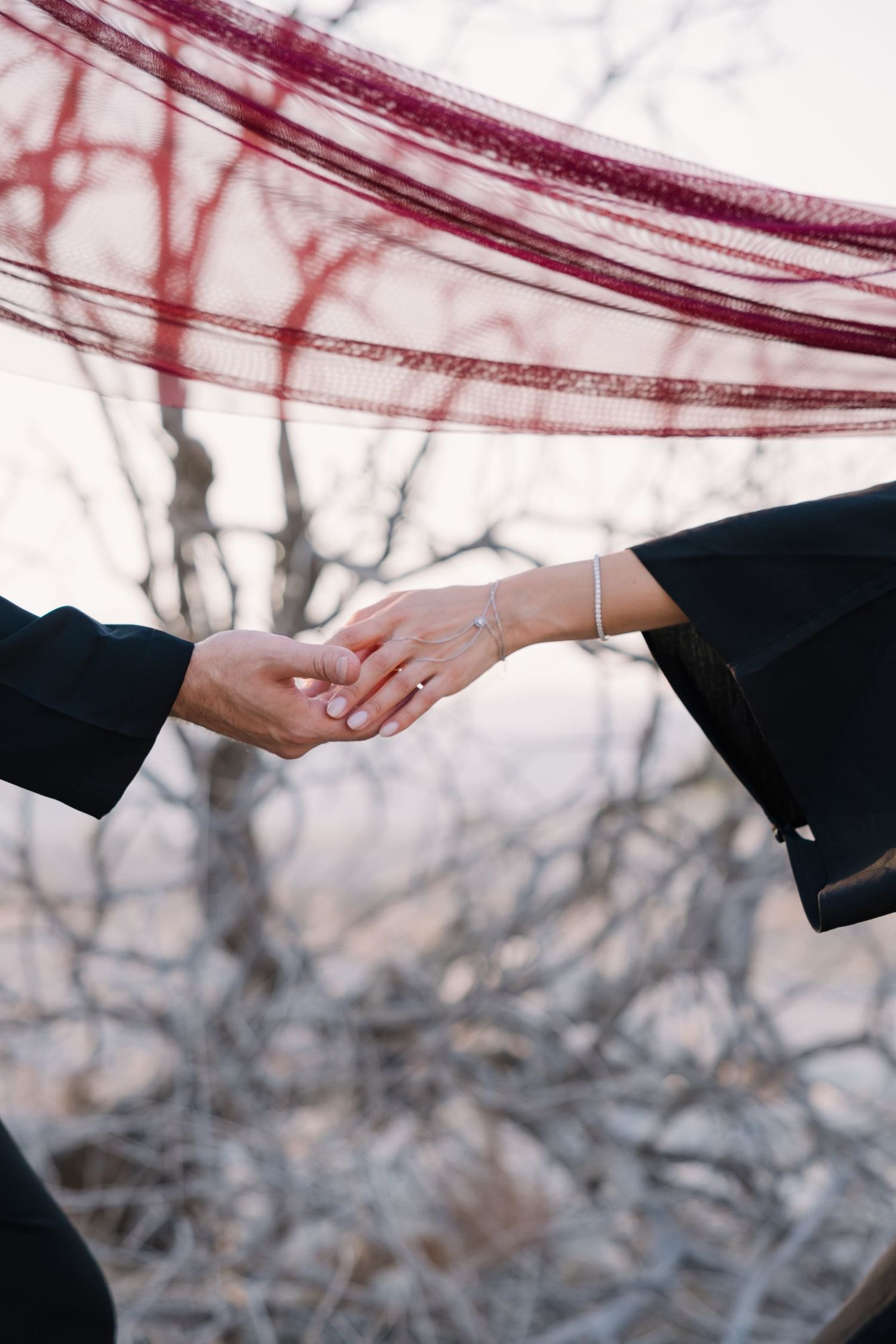 Two hands reaching to touch in a tender moment against a winter backdrop.