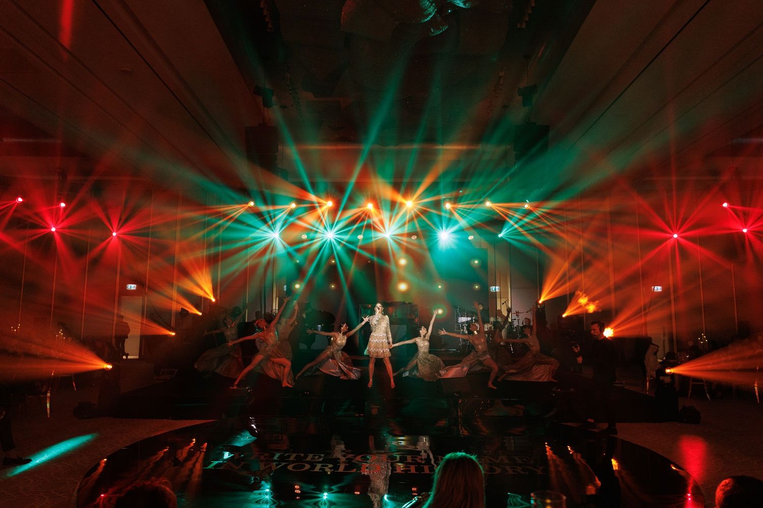 Concert stage lit with dynamic red and teal lighting effects during live performance.