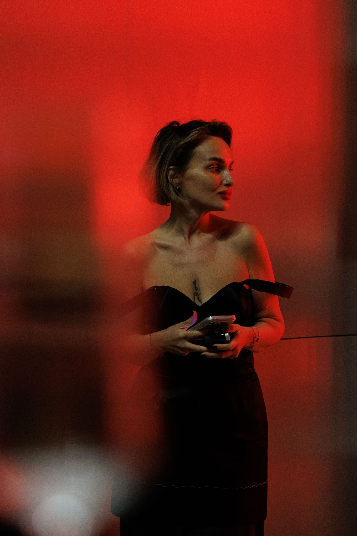Silhouetted figure shown in dramatic red lighting while holding an object in a theatrical pose.