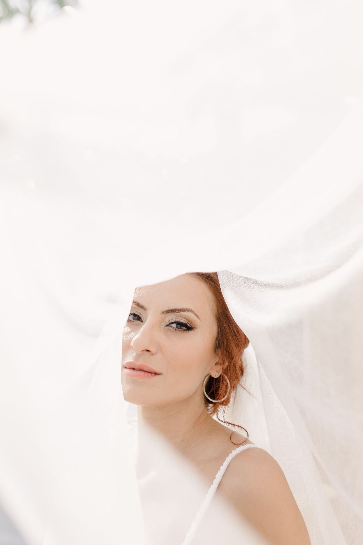 Ethereal bridal portrait with soft white veil and delicate jewelry.