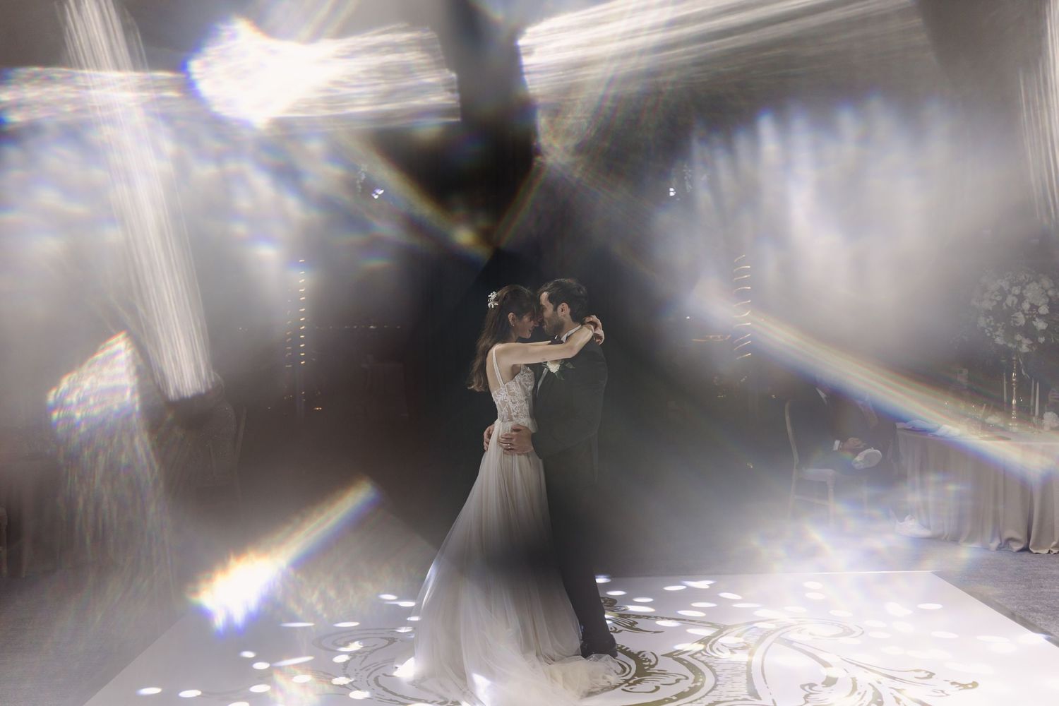 A couple shares their first dance as newlyweds under dramatic lighting and fog effects at their wedding reception.