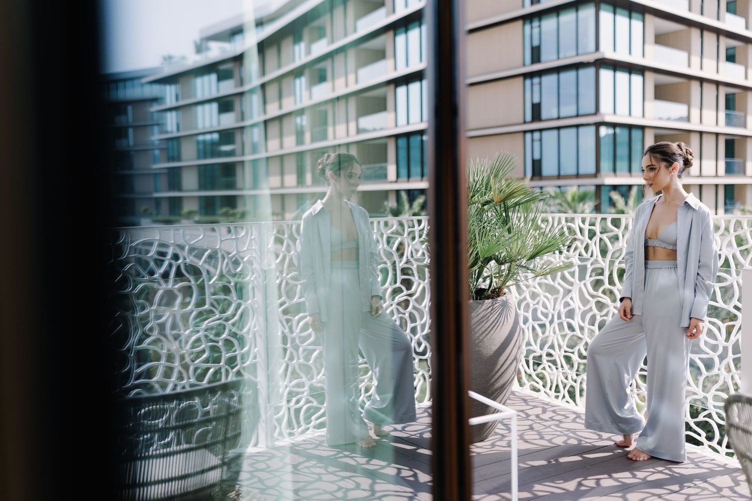Fashion photo through glass with decorative white metal railing and modern building backdrop.