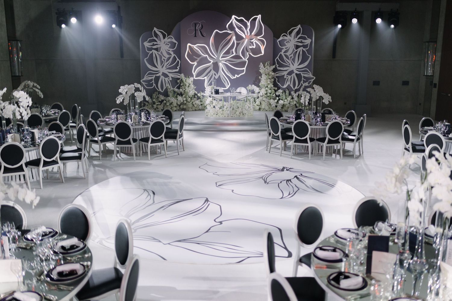 Modern wedding venue with dramatic lighting and artistic floral wall designs.