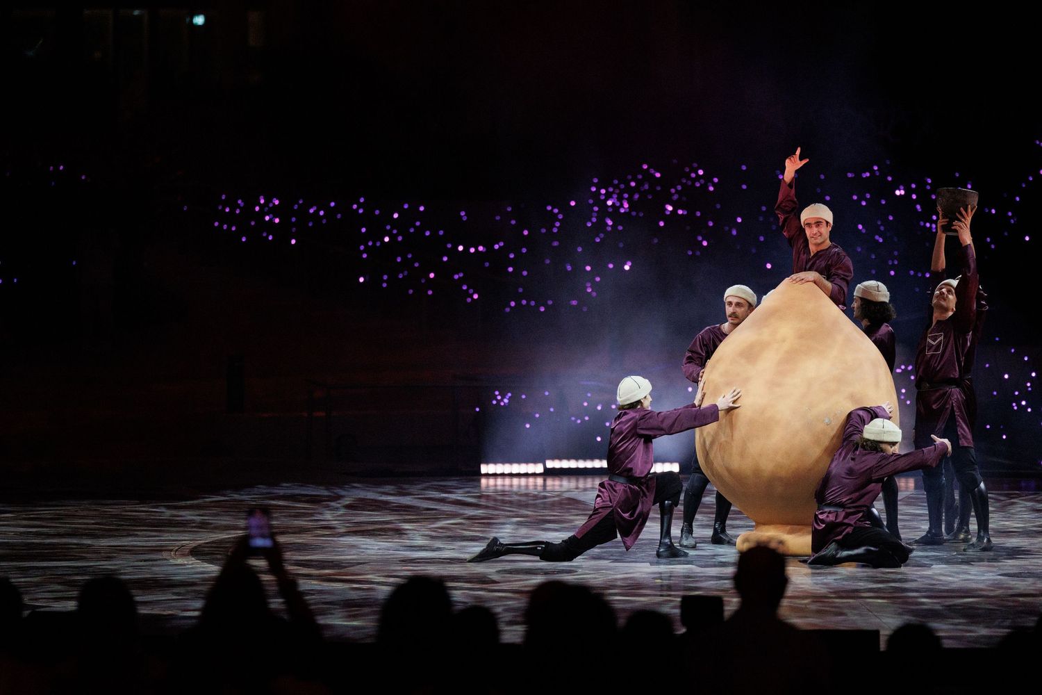 Dramatic stage performance with spotlights illuminating dancers in fluid motion on a dark stage.