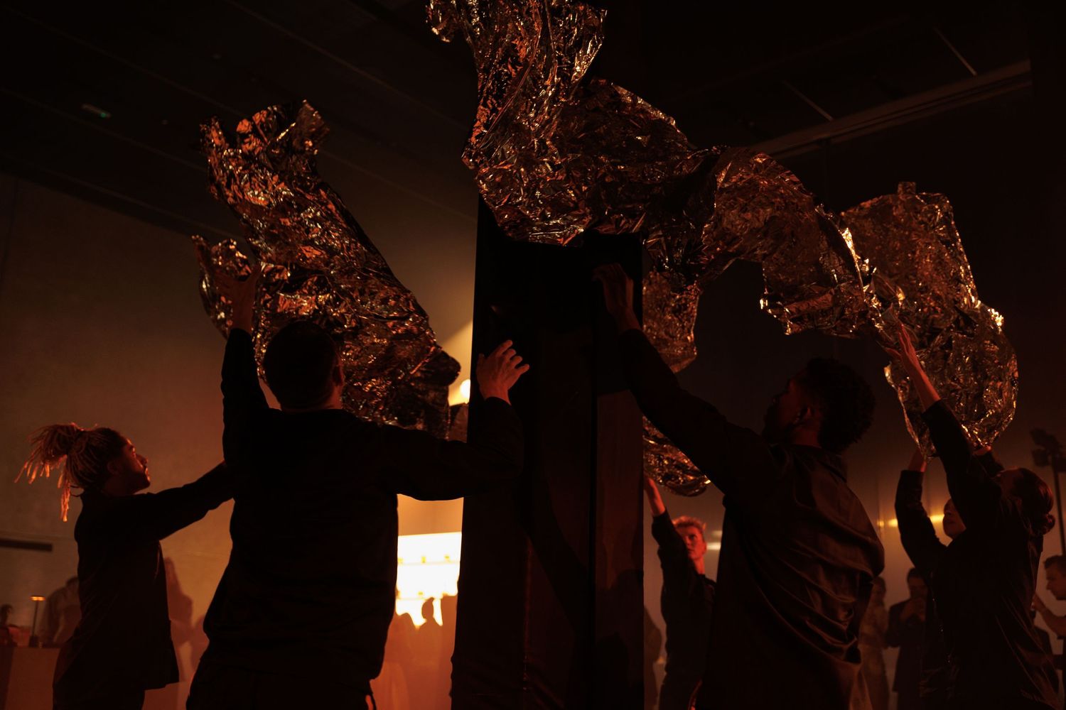 Group of people in dark silhouette against warm lighting creating dramatic shadows.