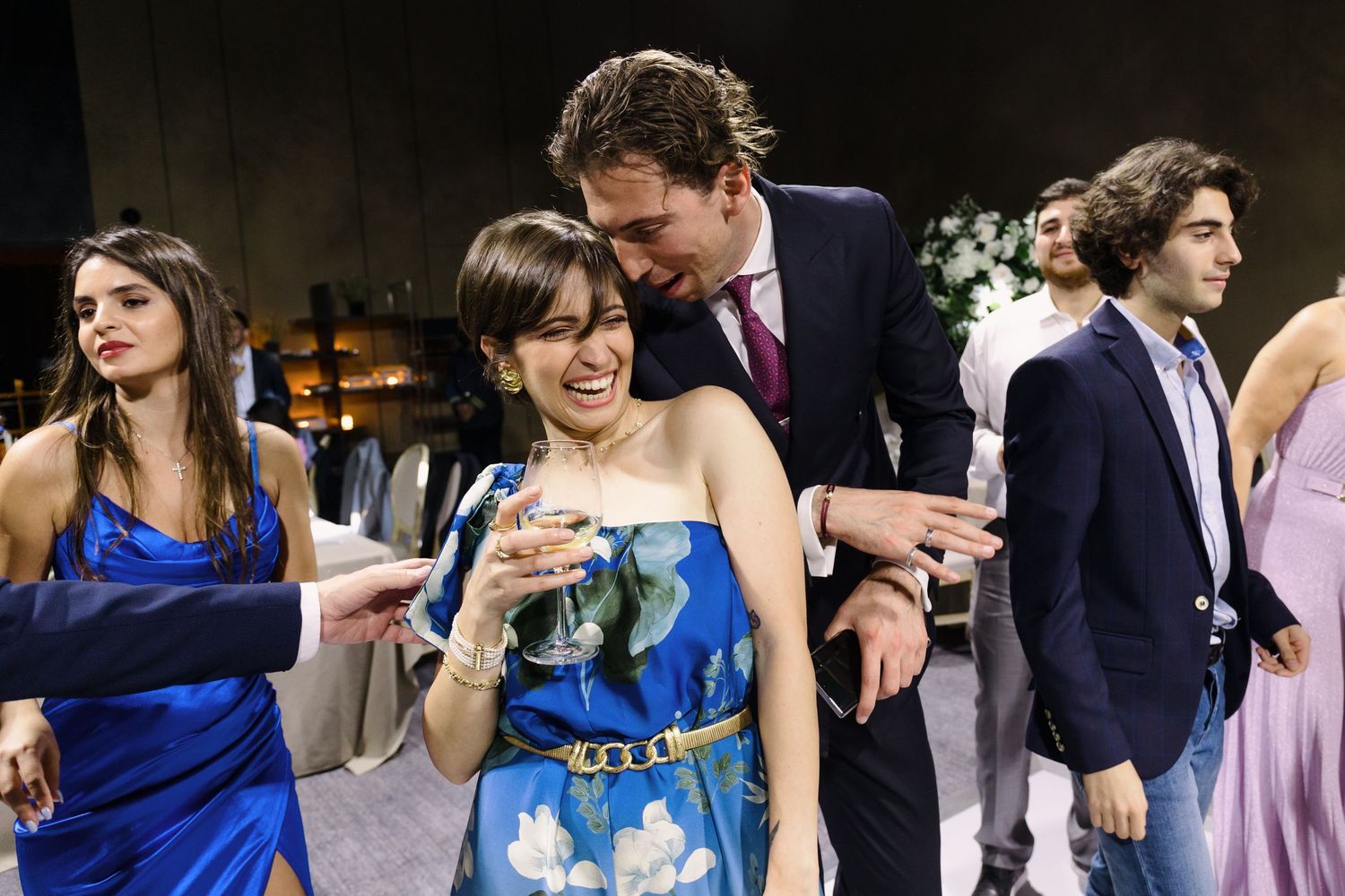 Wedding guests in colorful attire share laughter and drinks during the reception celebration.