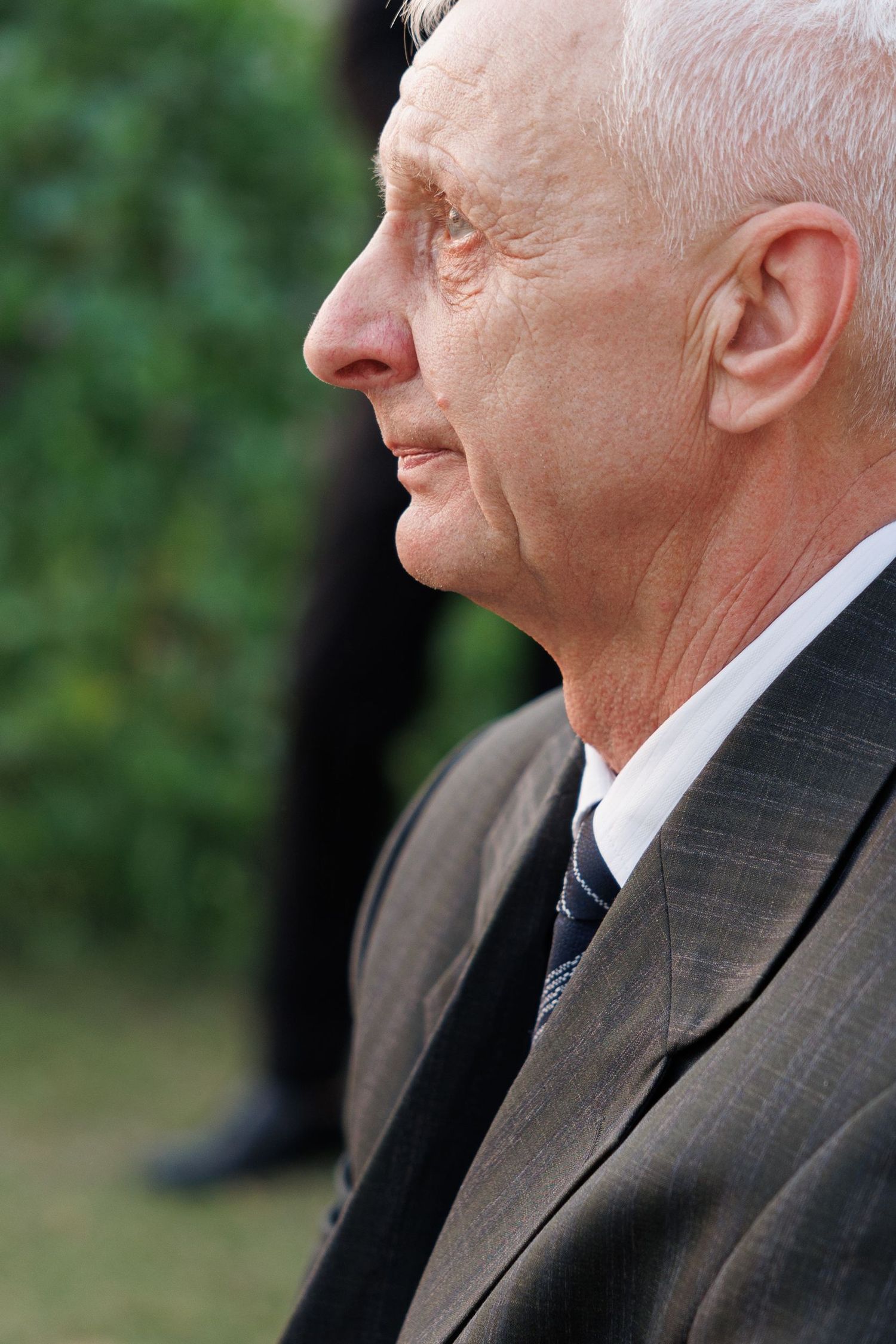 Profile view of a wedding guest in formal attire at an outdoor reception.