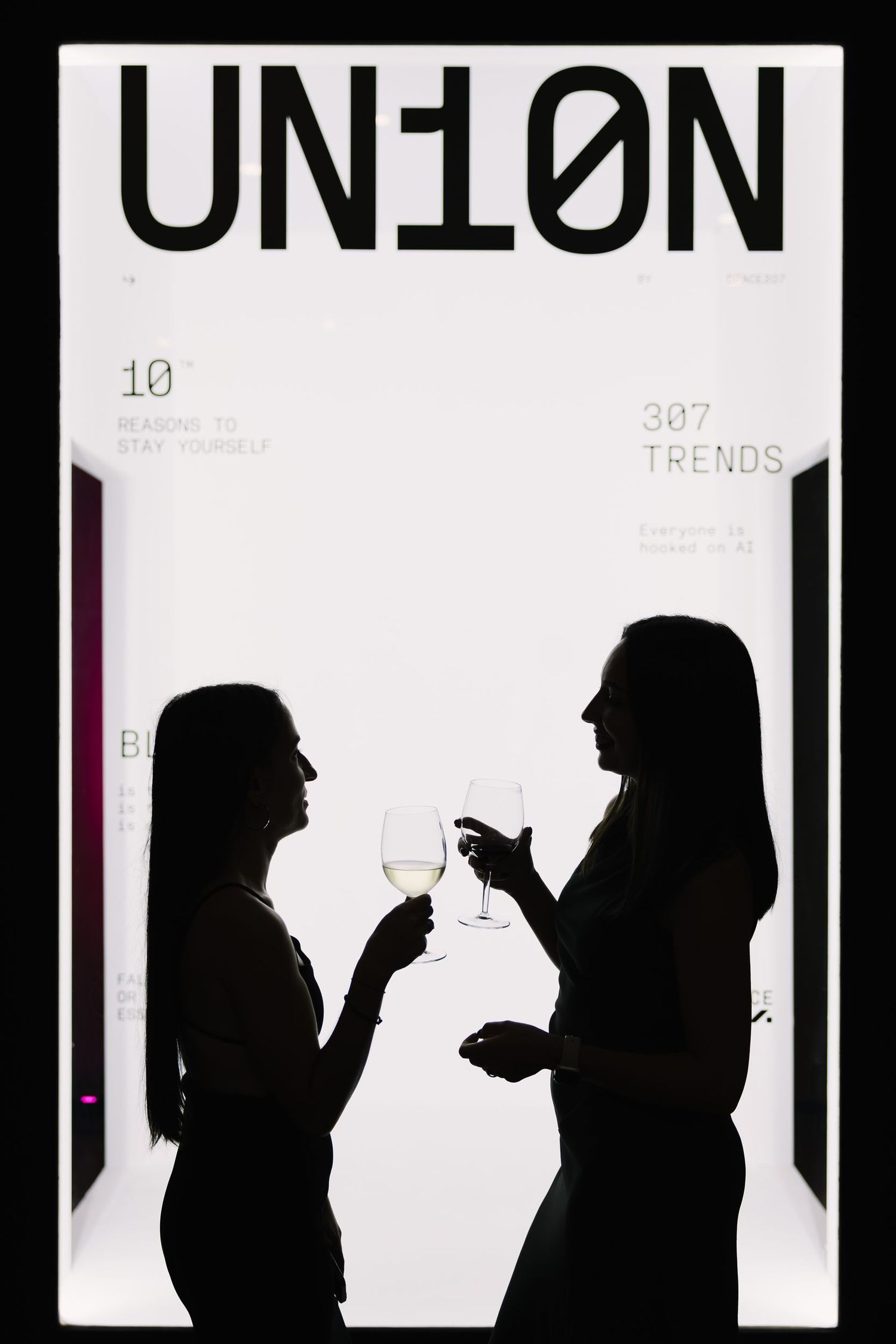 Silhouettes of people against illuminated white display panels with typography.