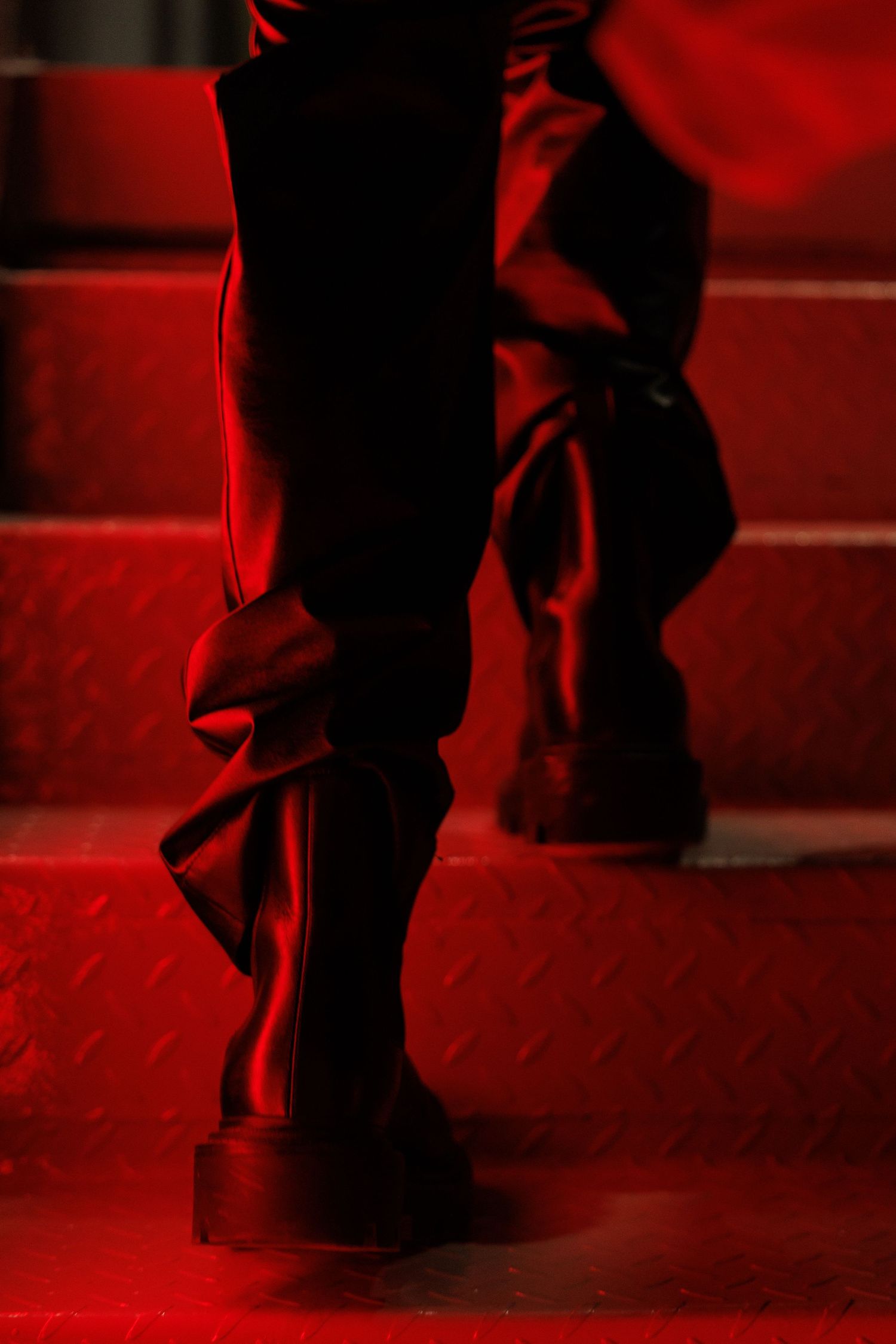 Silhouetted feet dancing in dramatic red lighting on a dark stage.
