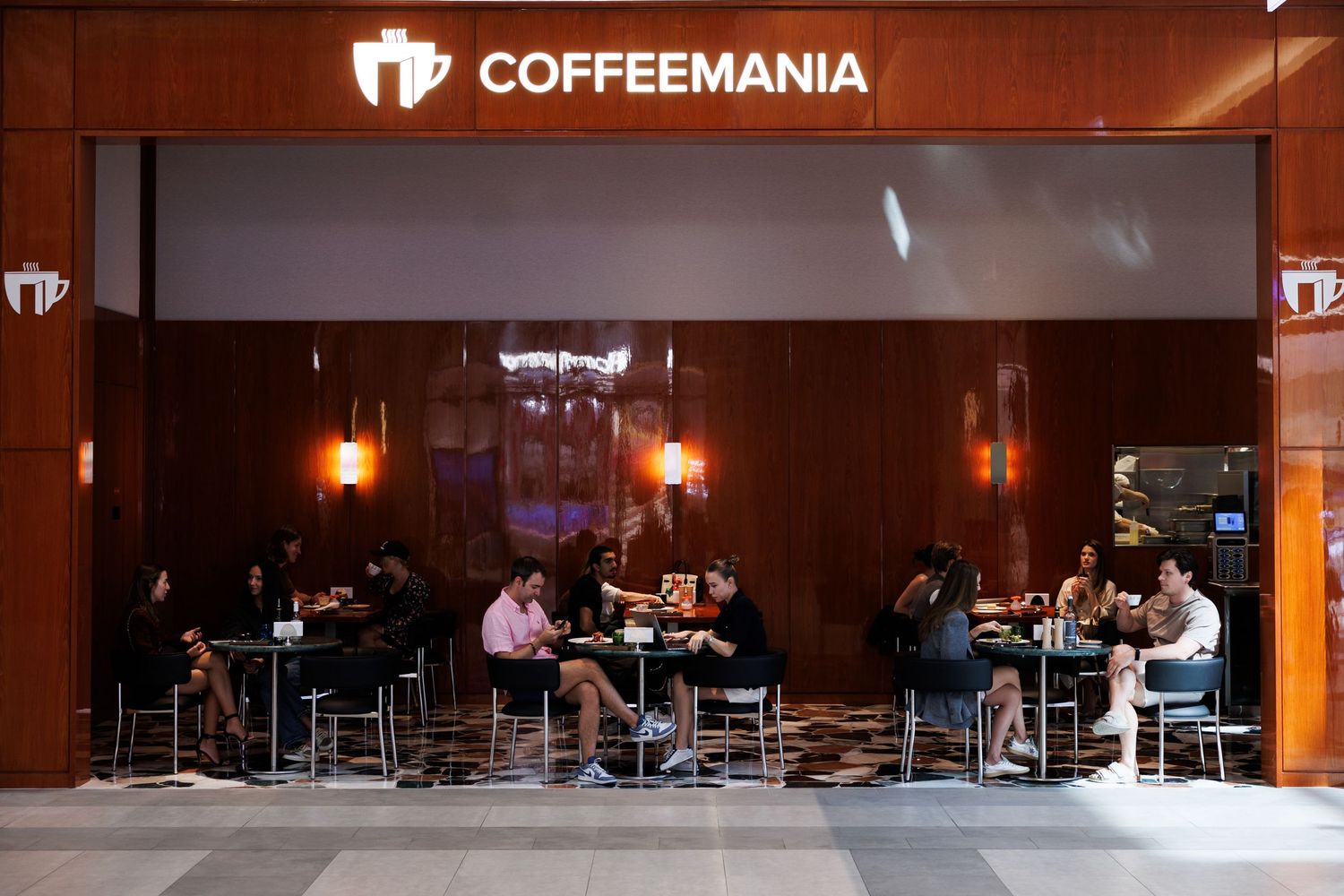 Outdoor seating area of Coffeemania cafe with customers dining at night.