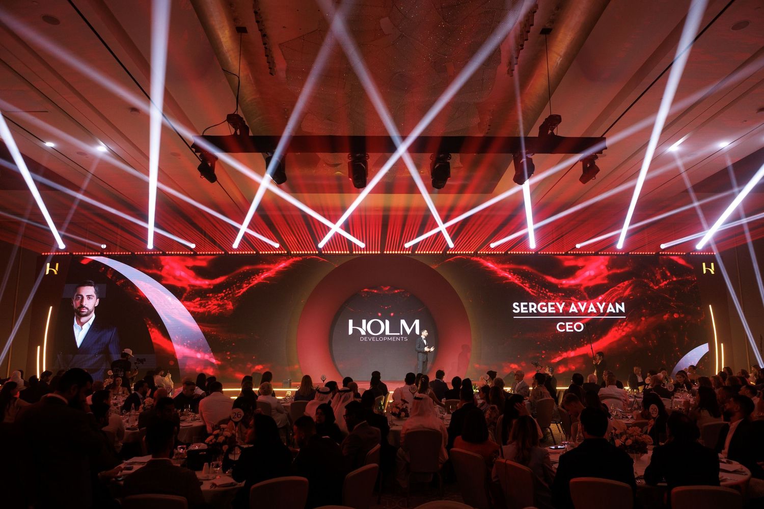 Wide view of corporate event space with dramatic cross-pattern lighting design in red.