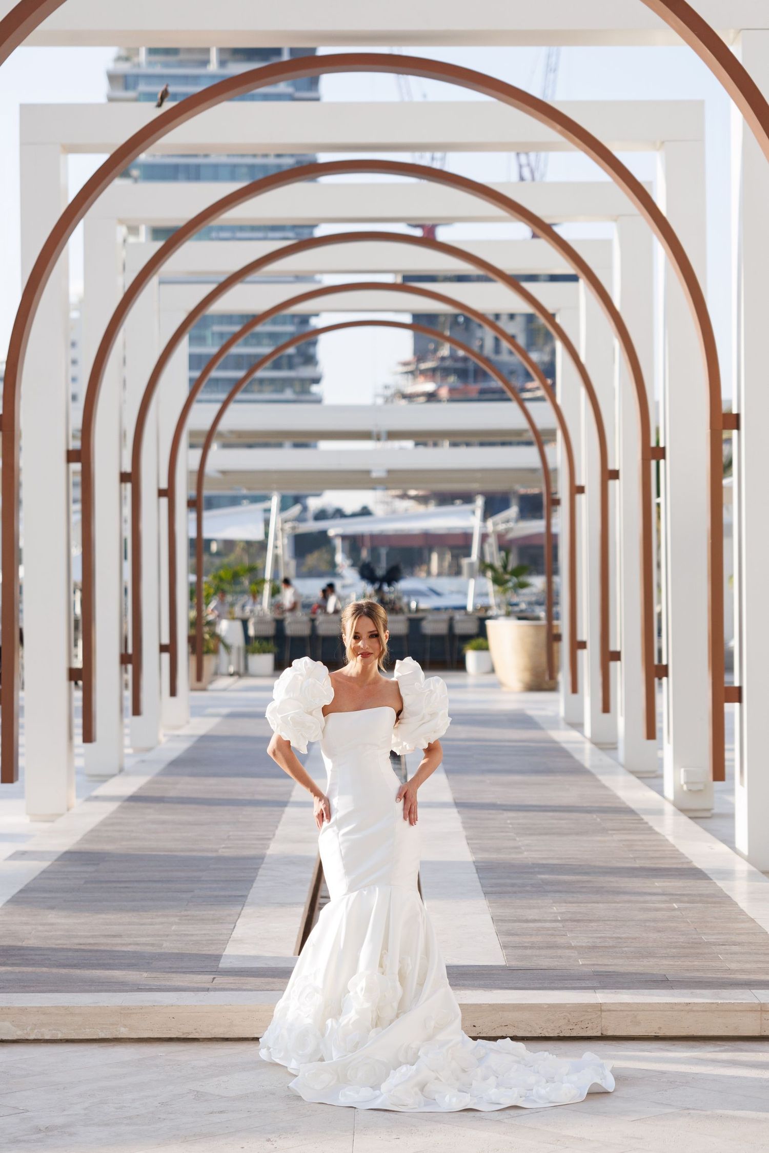 A wedding couple walks through a covered walkway with repeating arched columns.