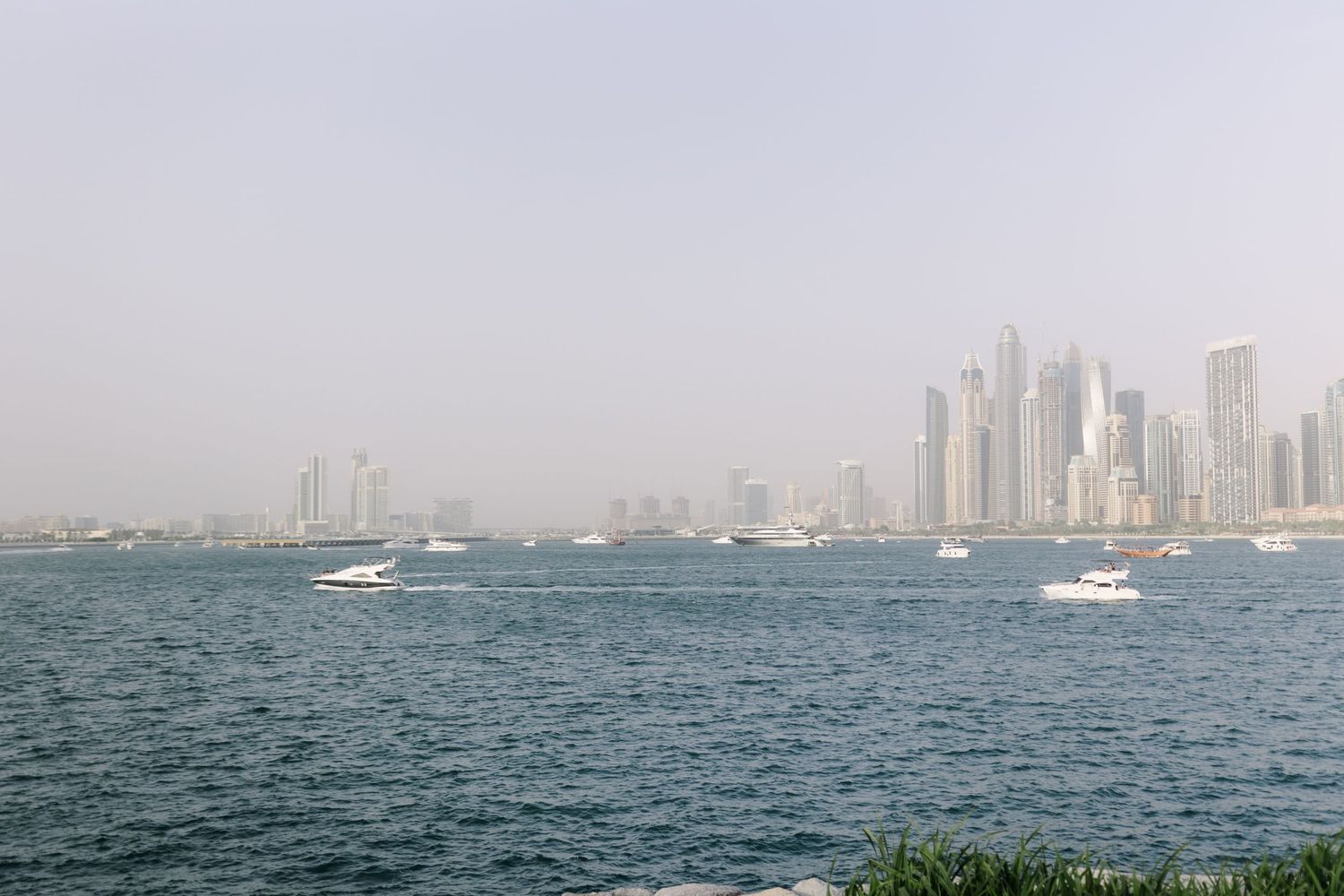 Panoramic view of a coastal cityscape with modern buildings and boats on the water.