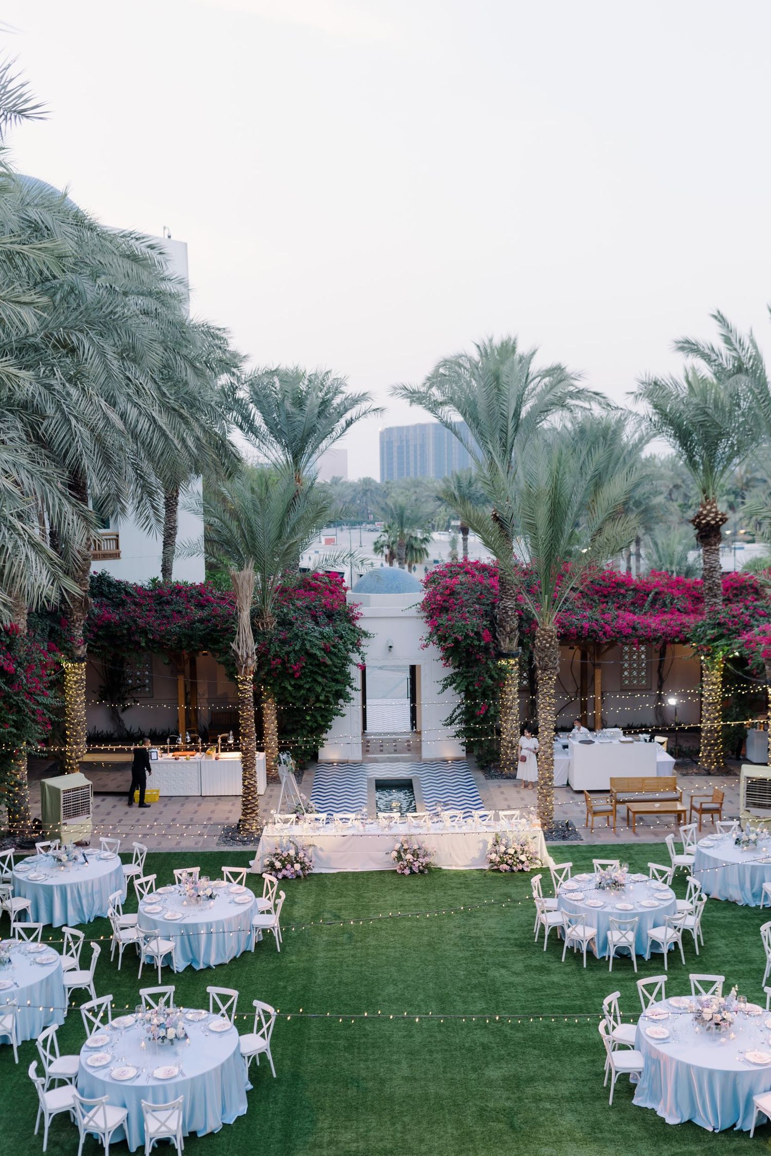 Tropical waterfront wedding venue with palm trees and round tables set for reception.