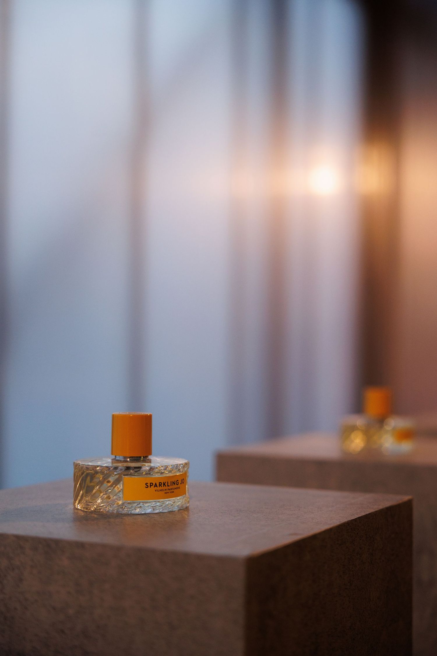 Perfume bottle displayed on minimalist wooden surface with soft focus lighting.