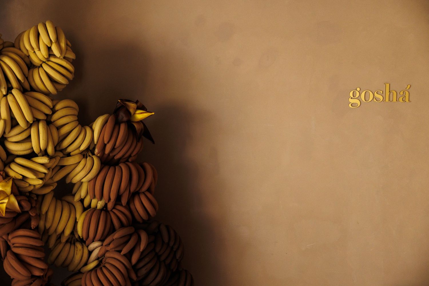 Artistic arrangement of fresh yellow bananas against neutral background.