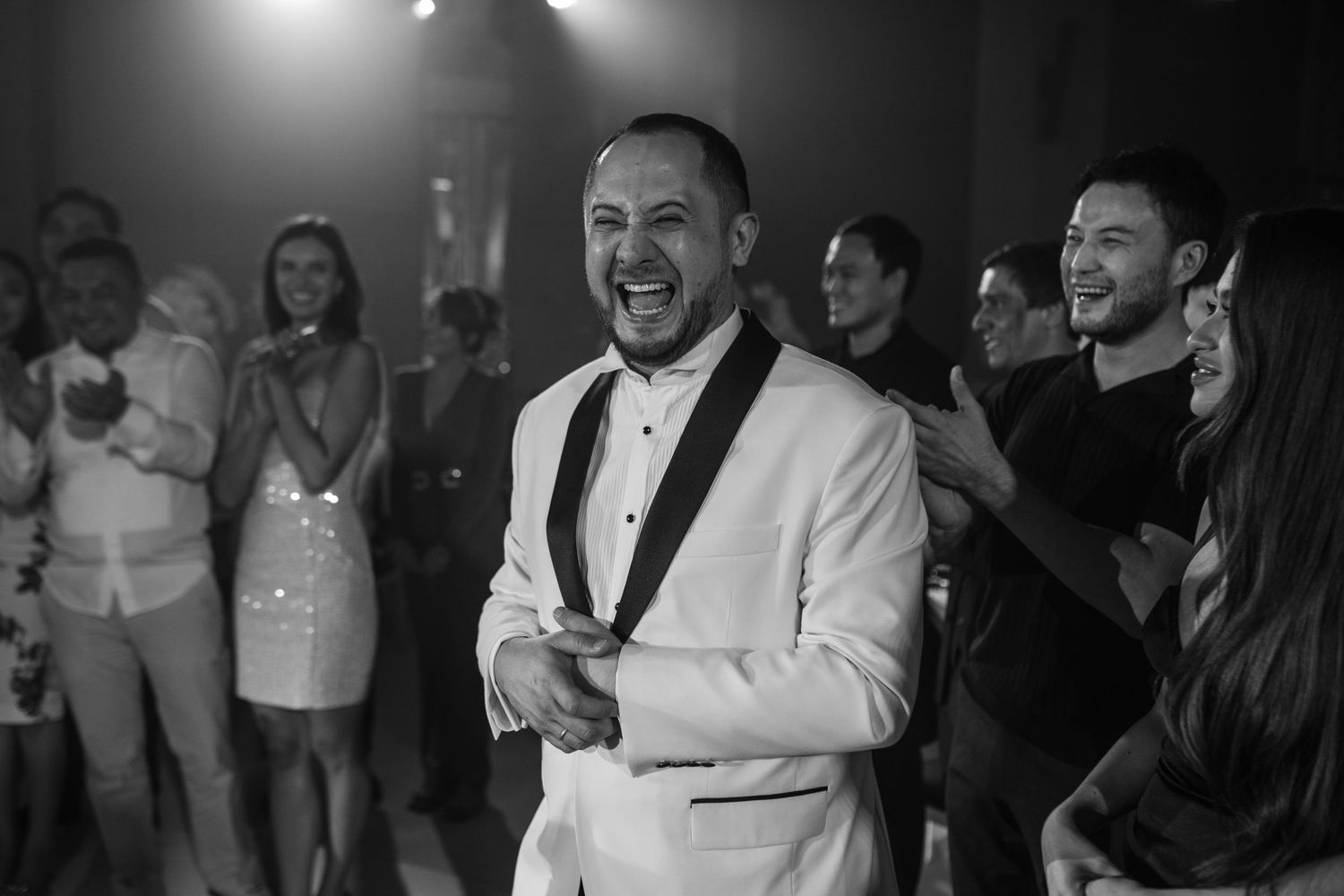 Monochrome wedding reception photo showing guests dancing and celebrating.