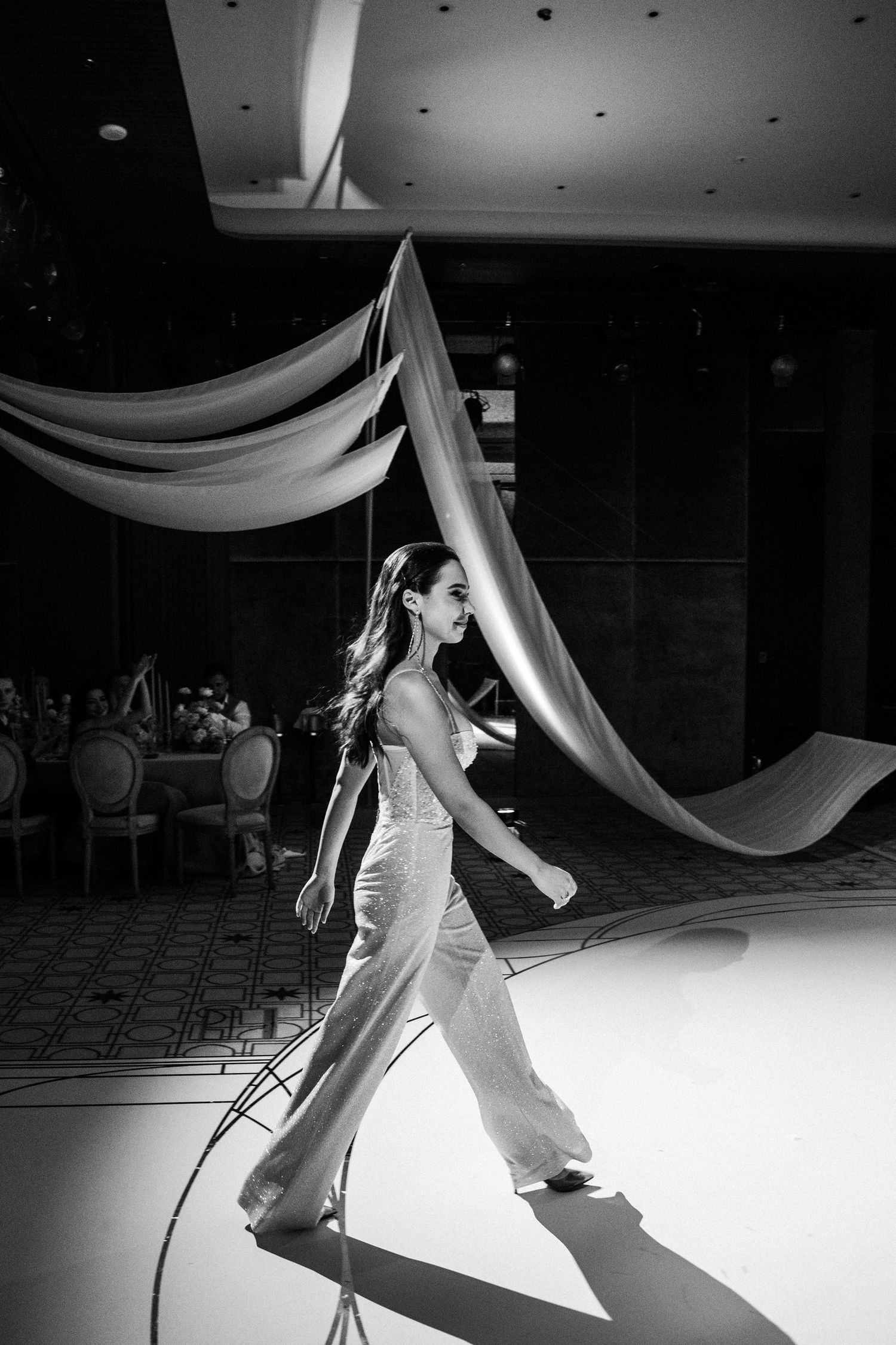 Black and white photo of dancers performing under draped fabric ceiling decor.