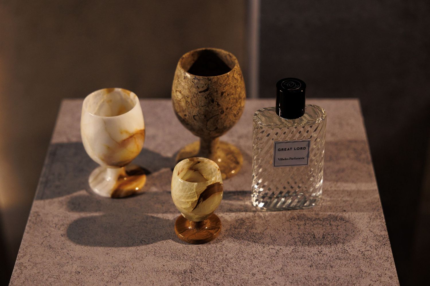 Perfume bottles and decorative objects arranged on a wooden surface in dramatic lighting.