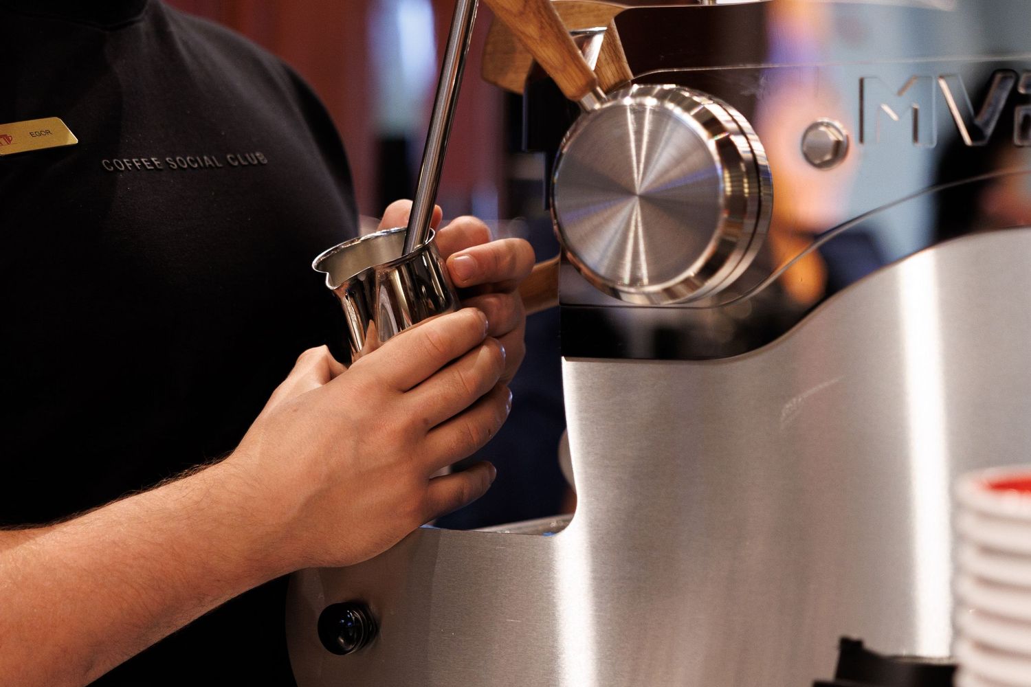Close-up of hands operating professional coffee equipment in cafe setting.