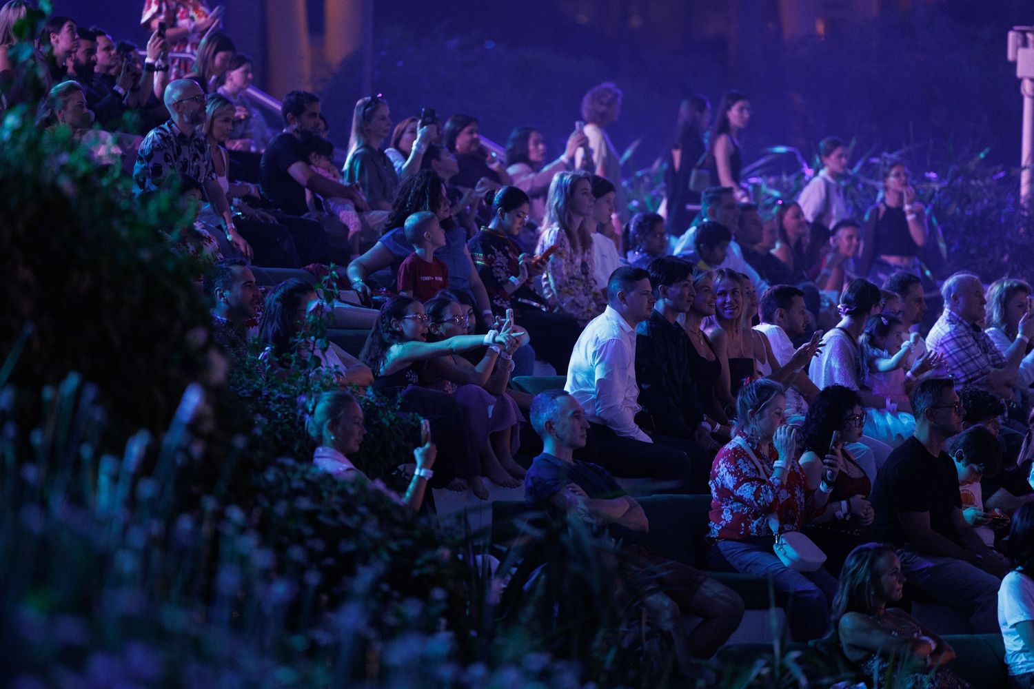 Concert crowd silhouettes against blue lighting under geometric dome structure.
