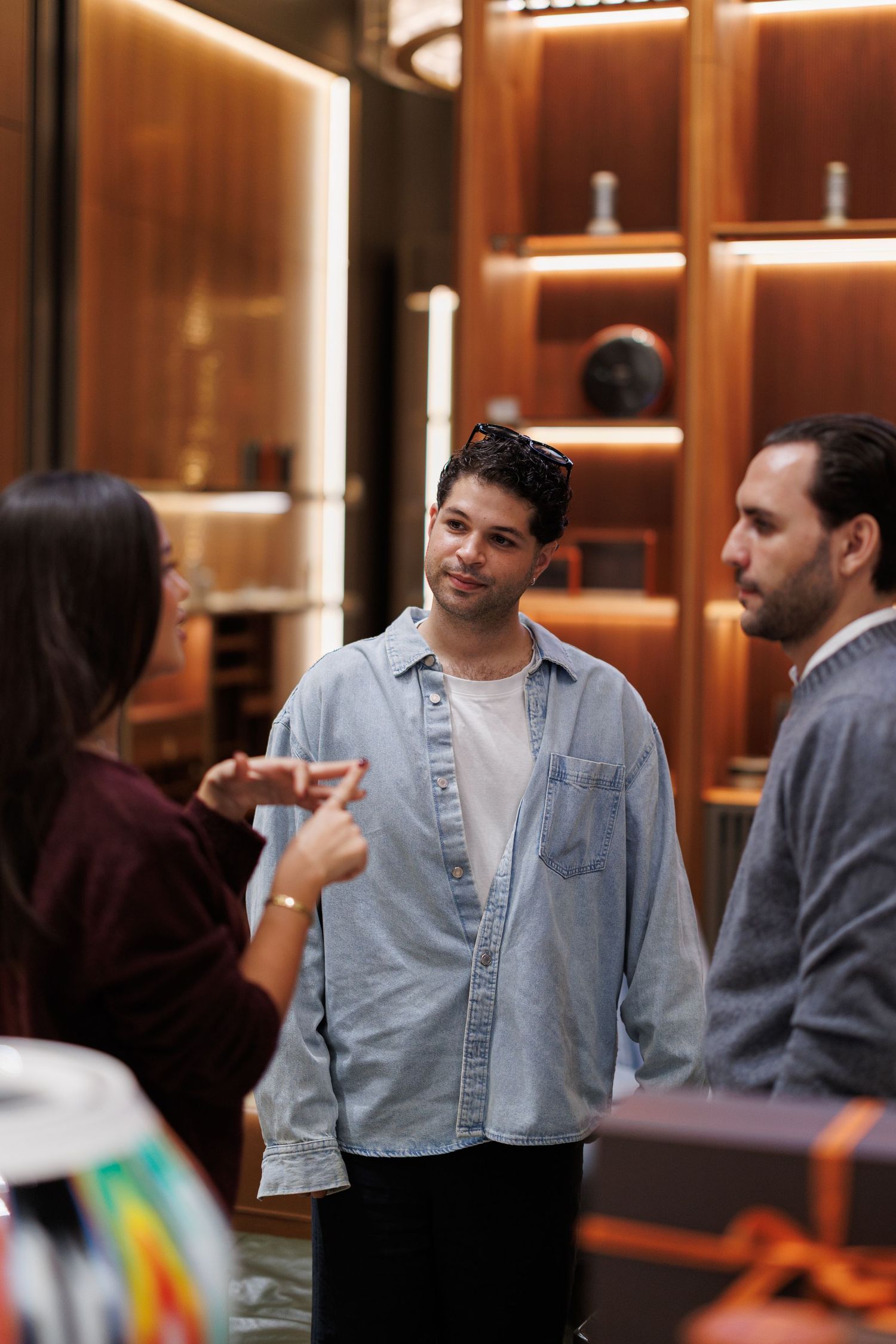 People having a conversation in a warmly lit retail space with wooden walls.