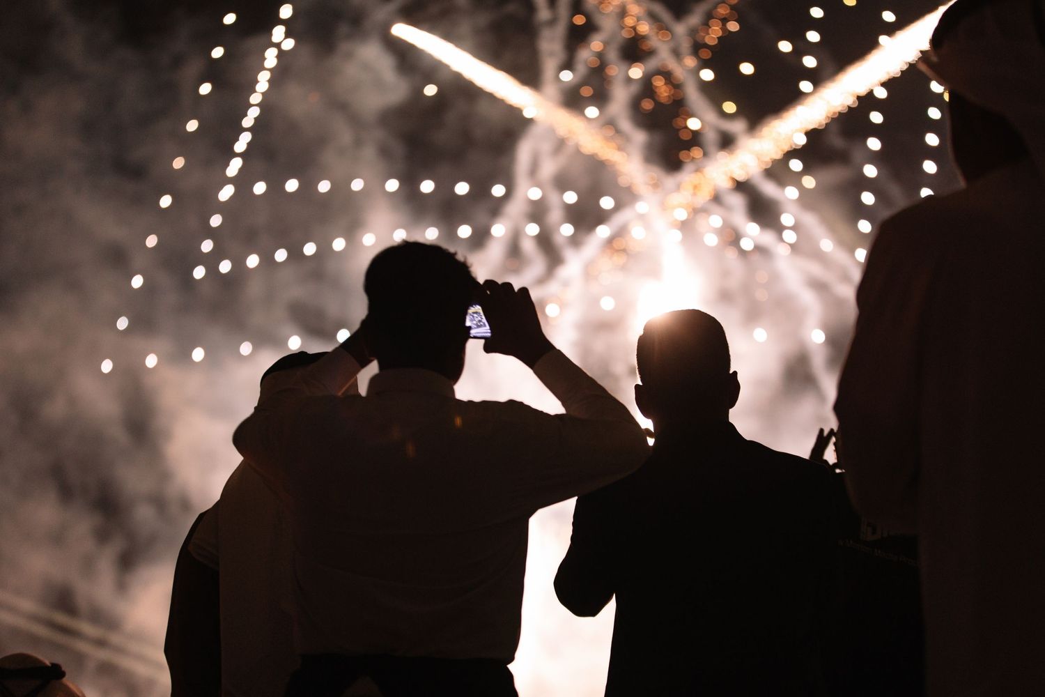 Silhouettes of spectators against a backdrop of sparkling lights and smoke effects.