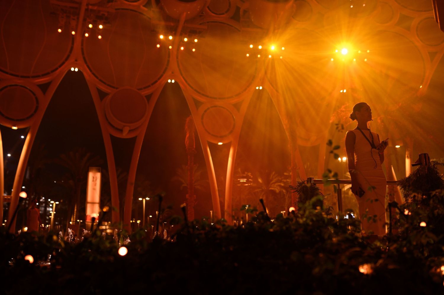 Warm orange stage lights illuminate geometric dome structure during event.