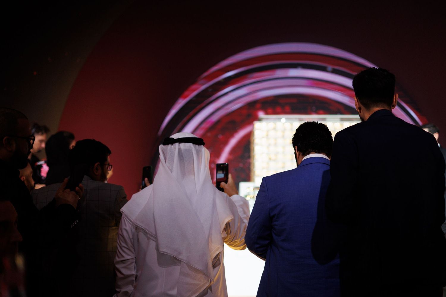 Silhouettes of people gathered in a dark room with red lighting effects.