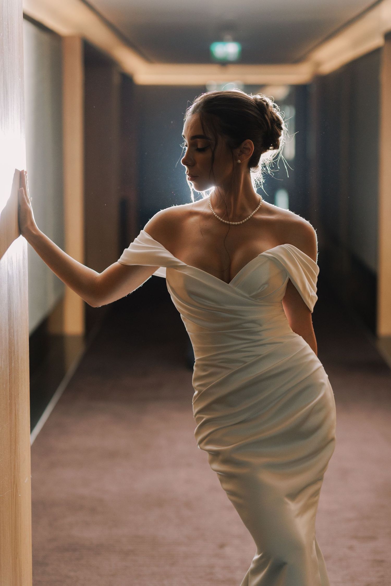 Bride in white gown moving gracefully through hotel hallway in artistic motion shot.