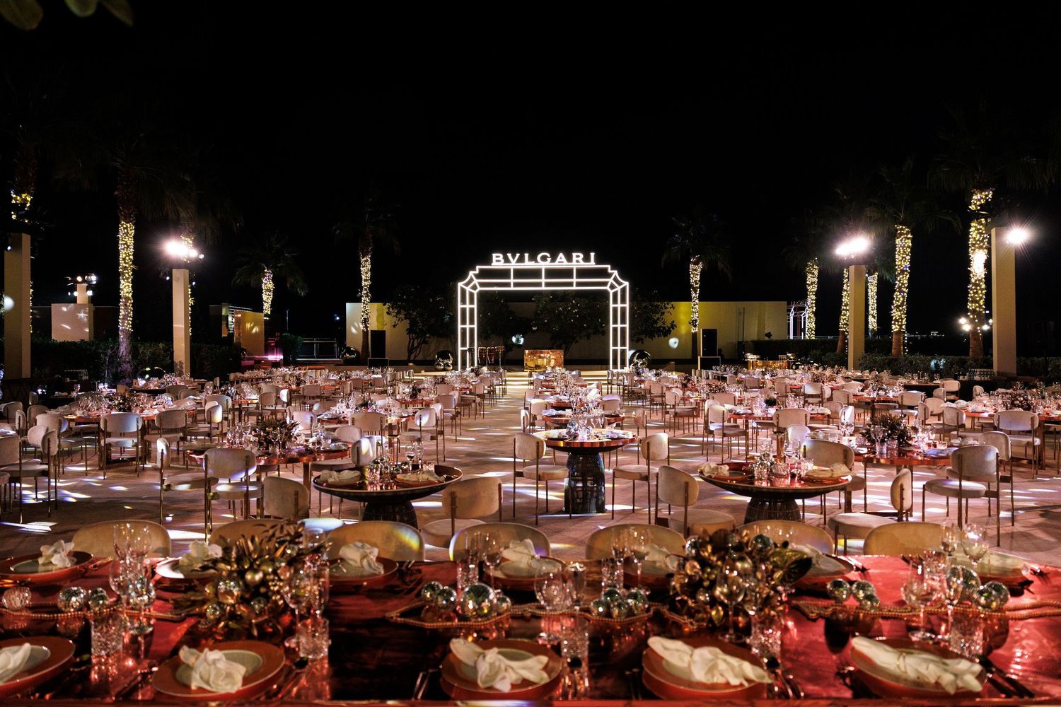 Panoramic view of a luxurious outdoor dining setup with multiple tables and lighting arrangements.