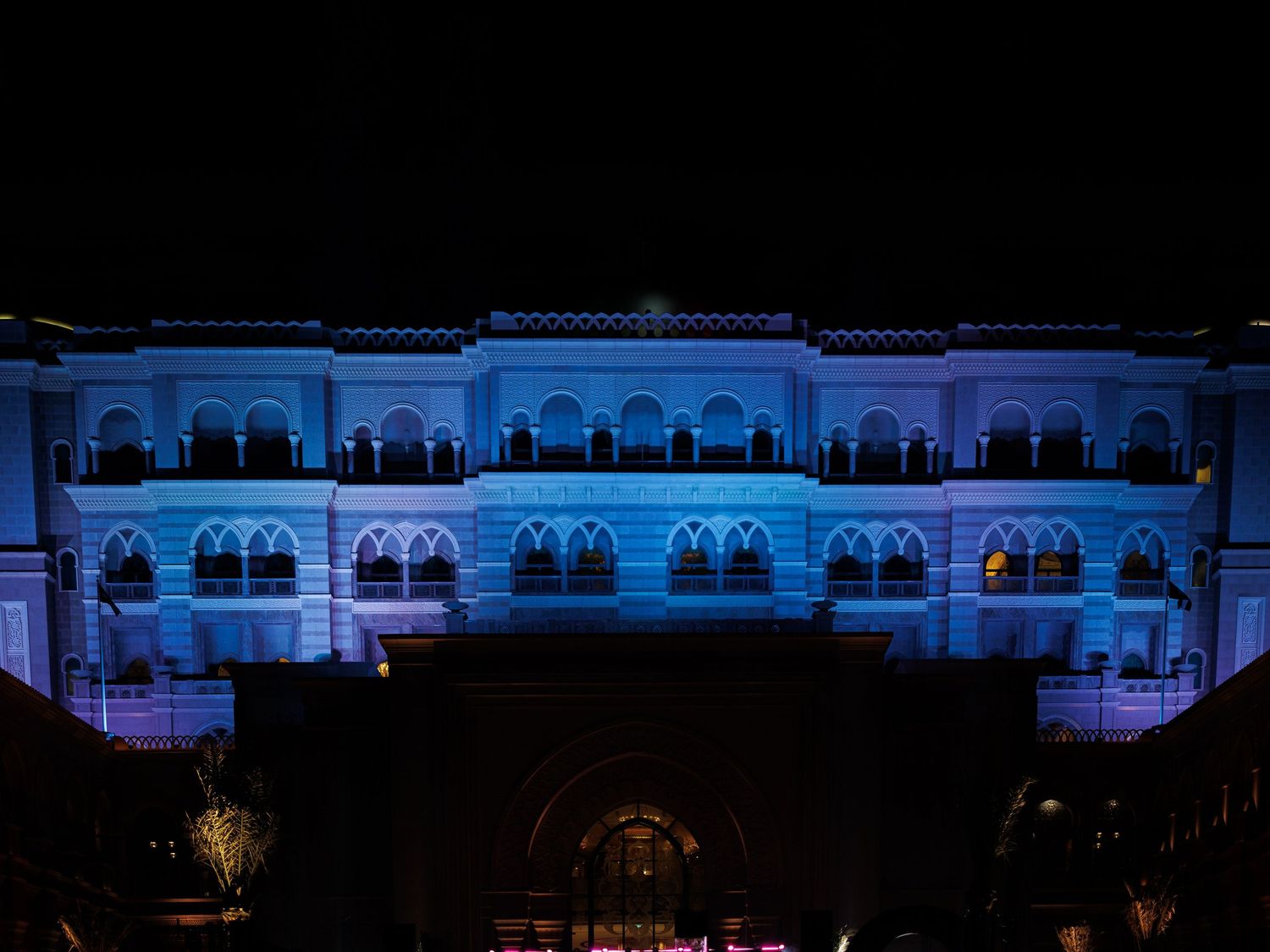 Architectural building illuminated at night with blue and red lighting creating a dramatic display along its facade.