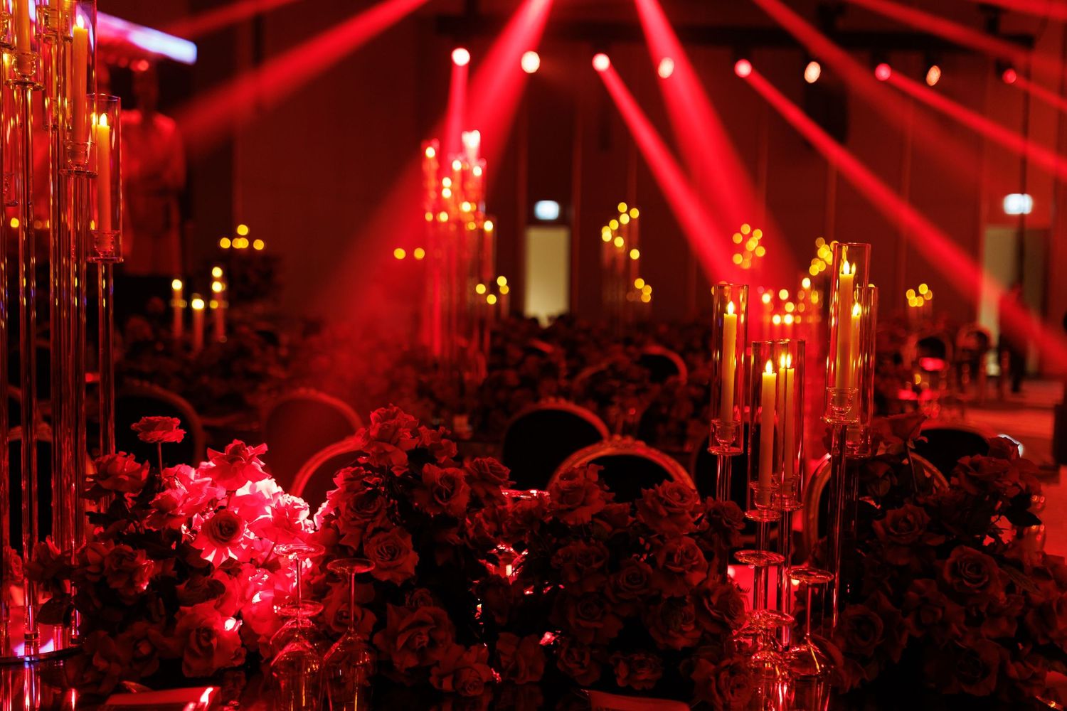 Nightclub or event space bathed in dramatic red lighting with silhouetted crowd.