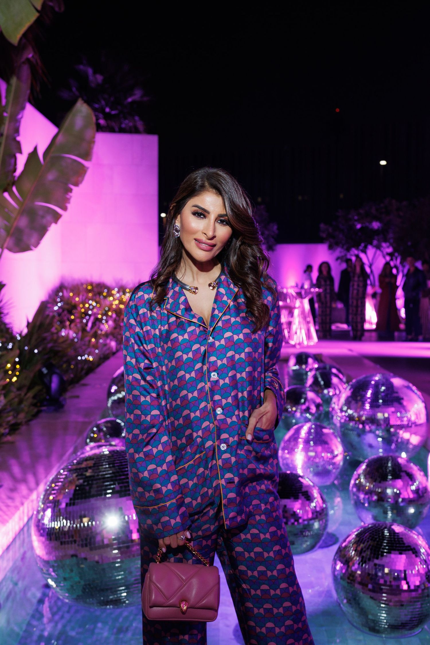 Models pose with disco balls in blue patterned outfits against purple lighting at a fashion event.
