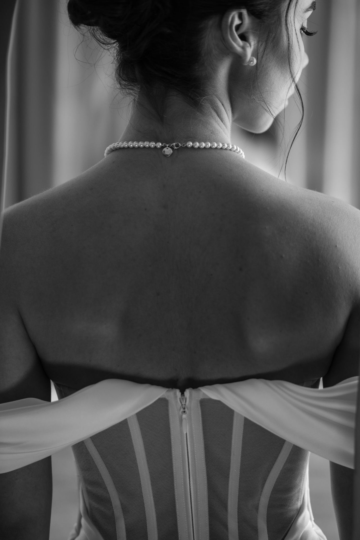 Artistic black and white photo of a bride's back showing strapless wedding dress details.