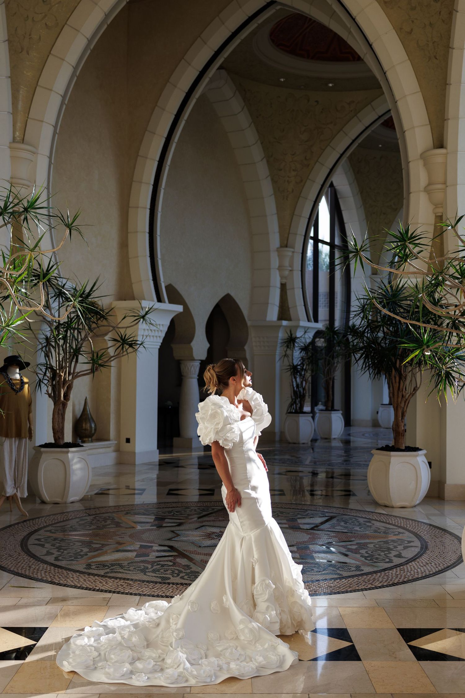 A wedding couple dances and twirls in a grand hall with arched columns and decorative flooring.