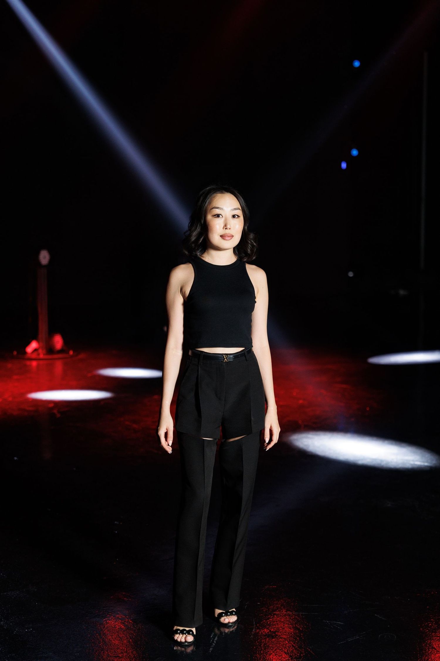 Fashion runway show with dramatic lighting and spotlights on a dark stage.